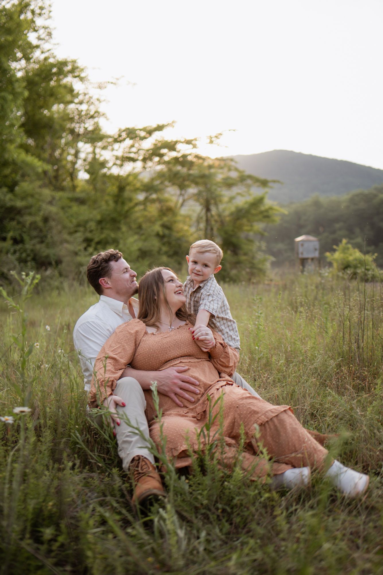Family sitting in a field looking at toddler, looking at camera during family session at raccoon mountain, Chattanooga TN