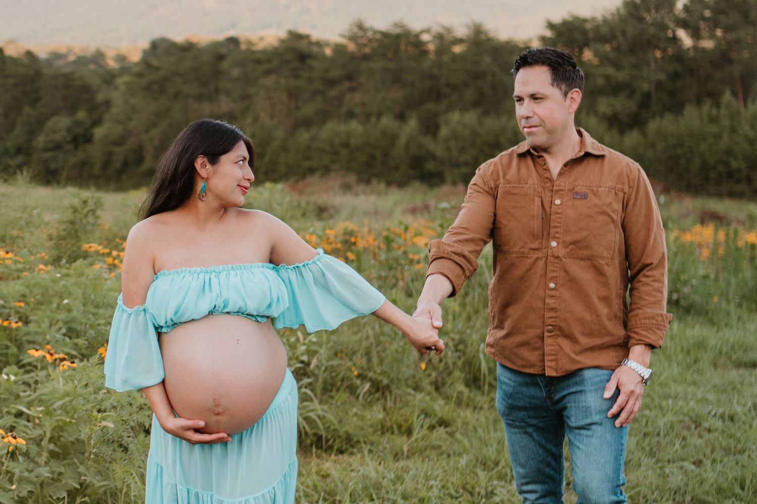Itzayana walking and looking back at husband in flower field at Fox Mountain Farms, Chattanooga, TN – maternity session, soft summer light