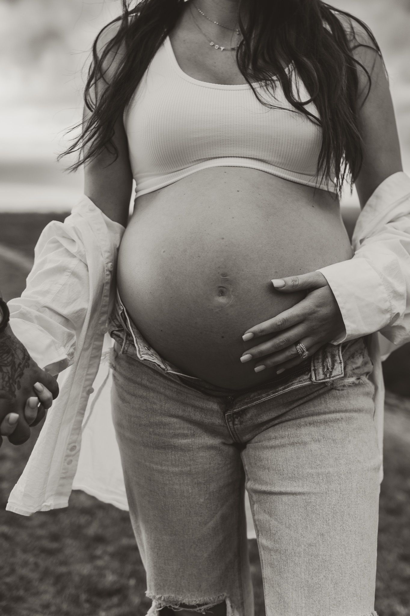 Black and white close up of expecting mom walking and holding bump during maternity session on raccoon mountain in chattanooga tn, overlook