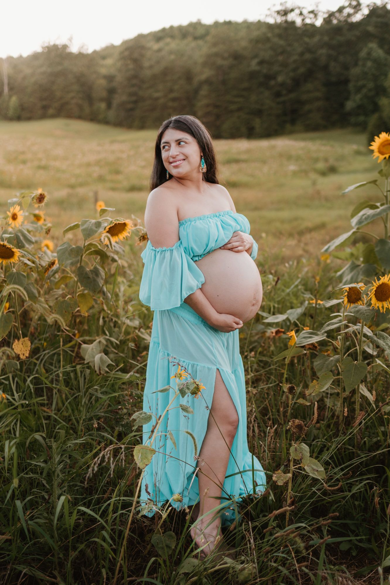 Expecting mom standing in a sunflower field during golden hour maternity session at Fox Mountain Farm in Rising Fawn, Georgia
