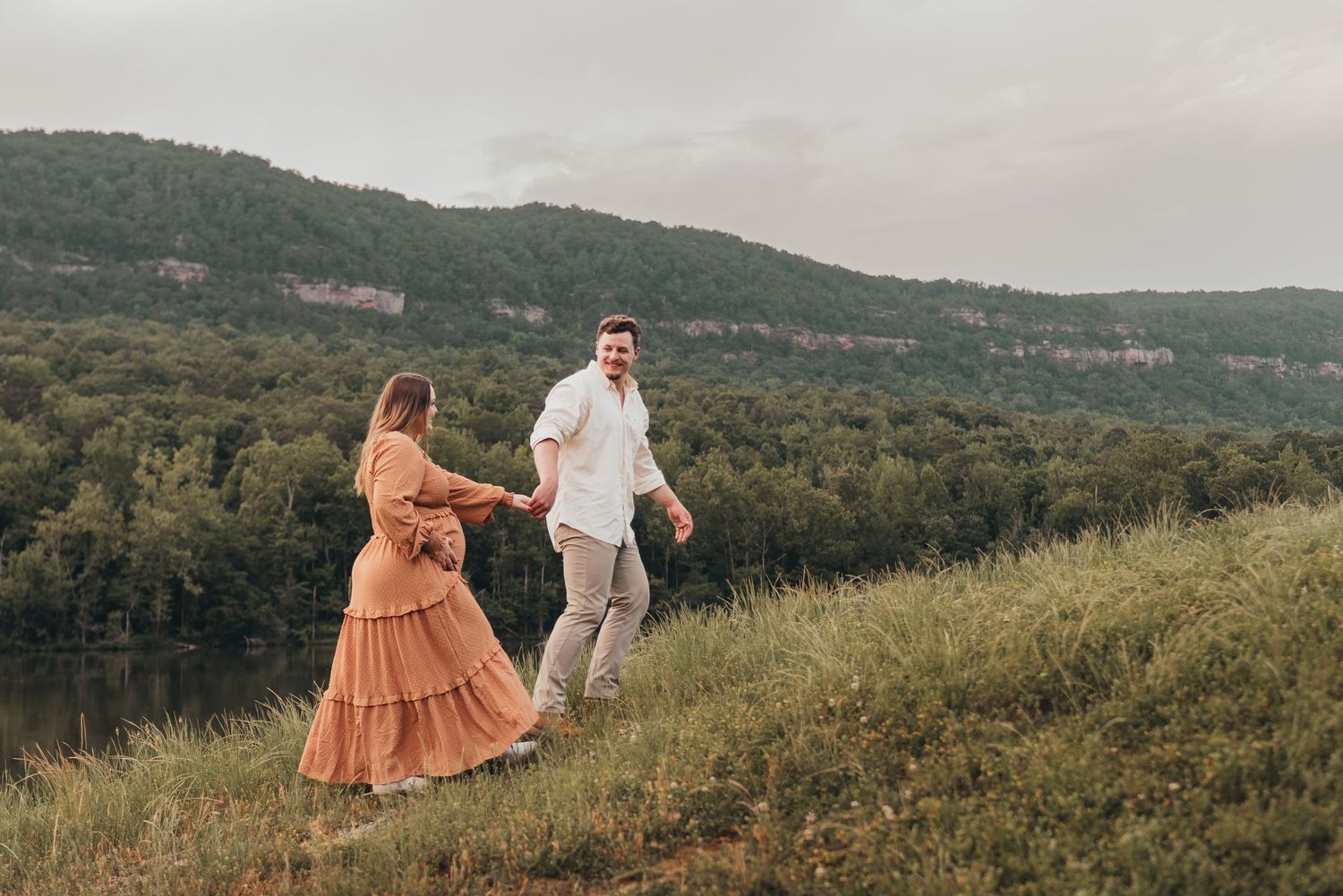 Couple walking in a field in Chattanooga, TN – family maternity session, soft summer light, mountains and water