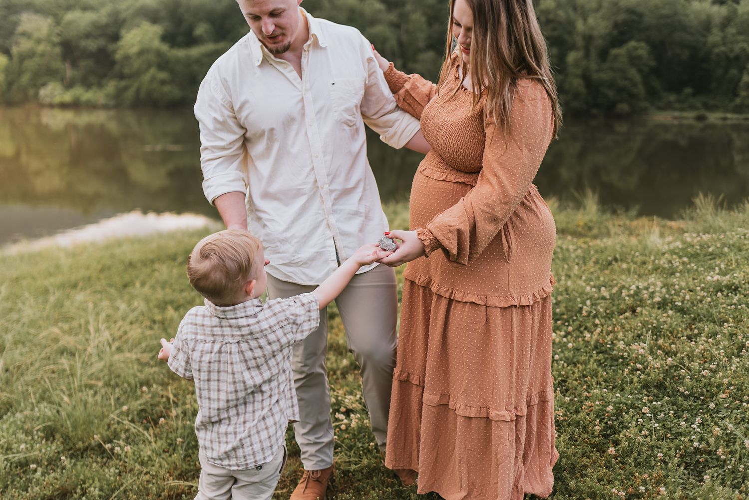 Toddler handing flowers to parents during family session at raccoon mountain, chattanooga TN, water and mountains in background