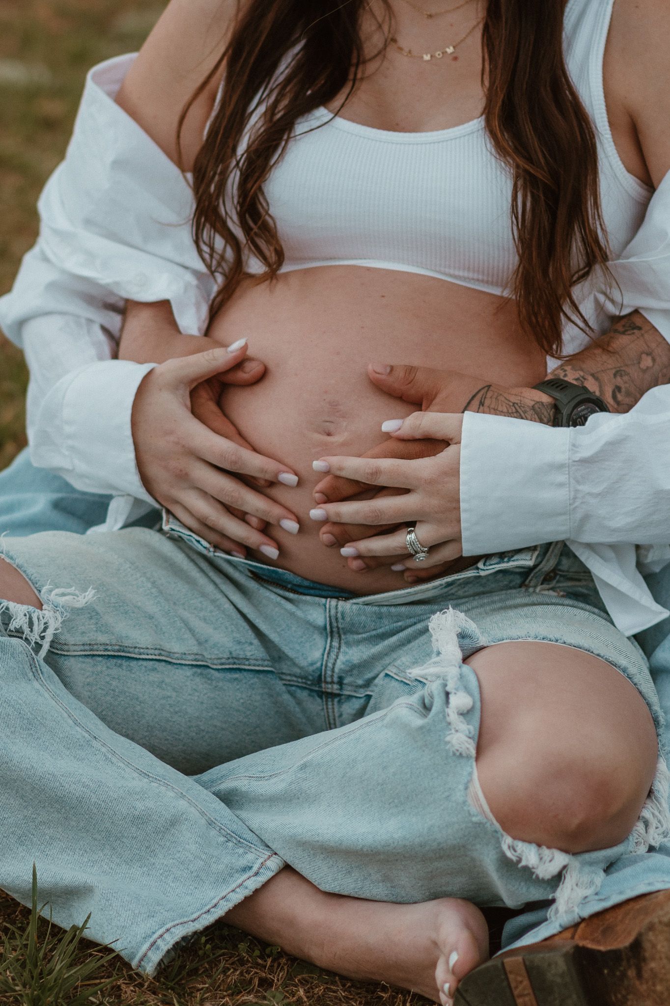 Close up of expecting couple sitting and holding baby bump hands together during maternity session on raccoon mountain in chattanooga tn
