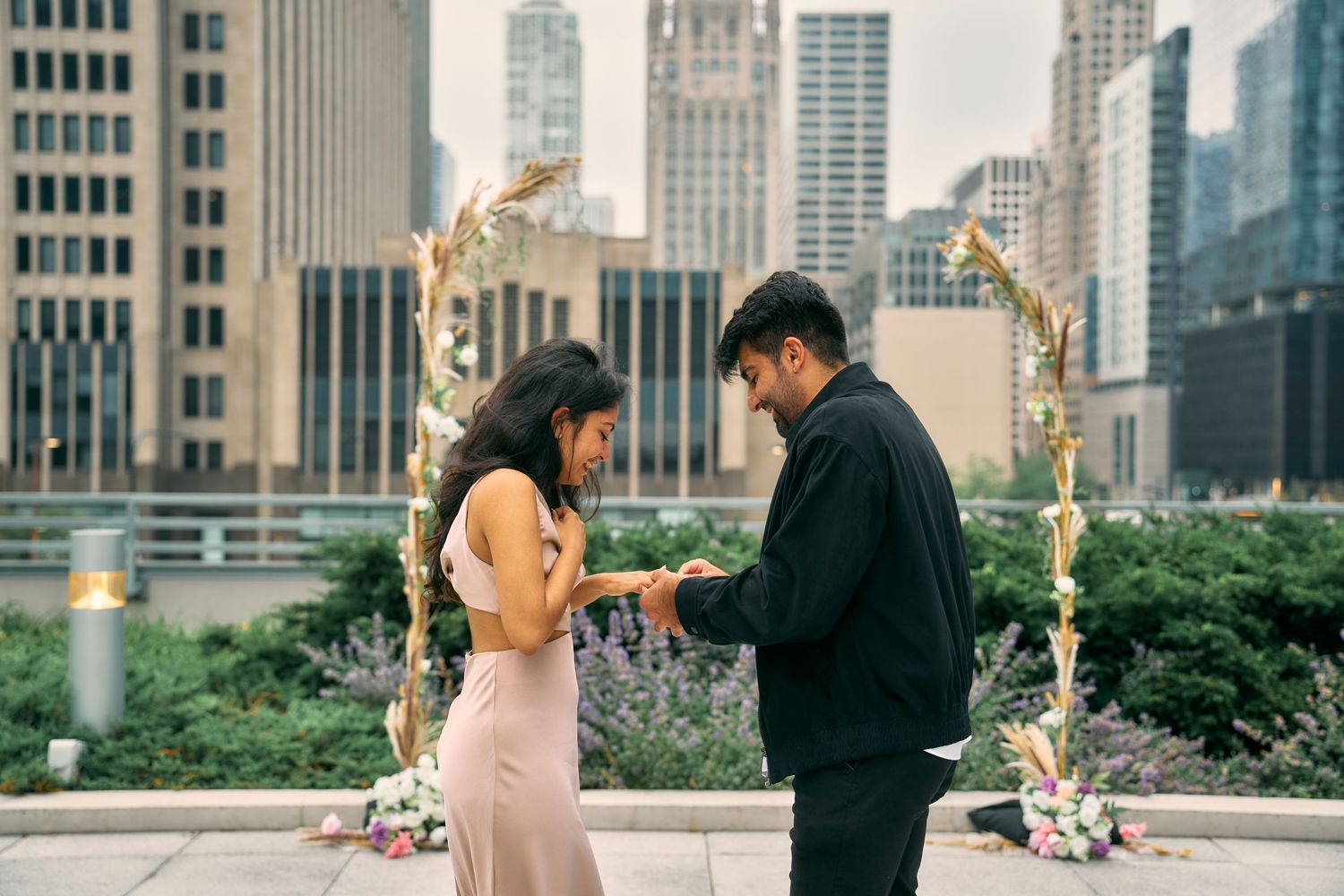 A couple shares a special moment during a rooftop proposal in New York City with skyscrapers in the background.