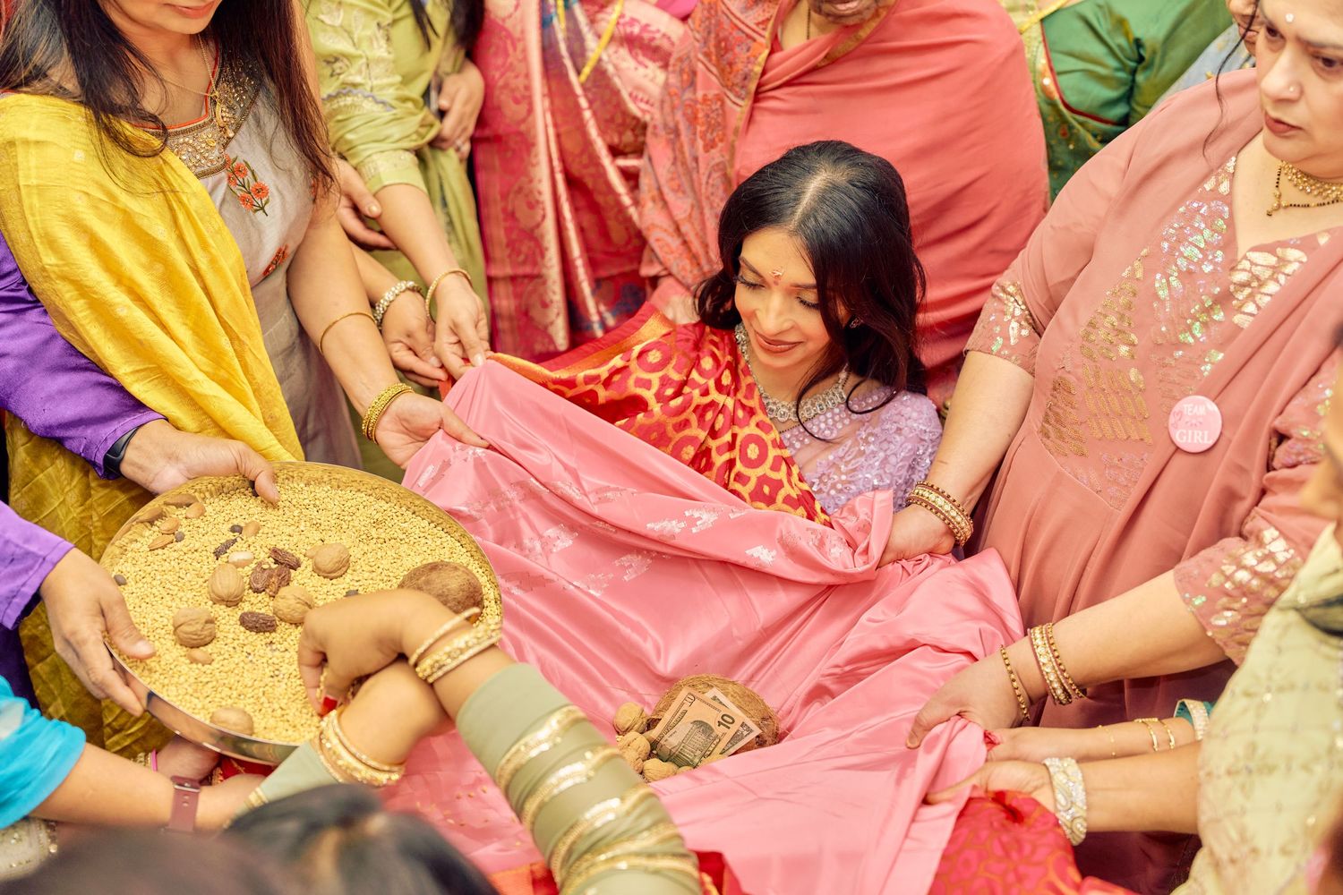 People in vibrant traditional Indian outfits celebrate a cultural ceremony with colorful fabrics and decorative items.