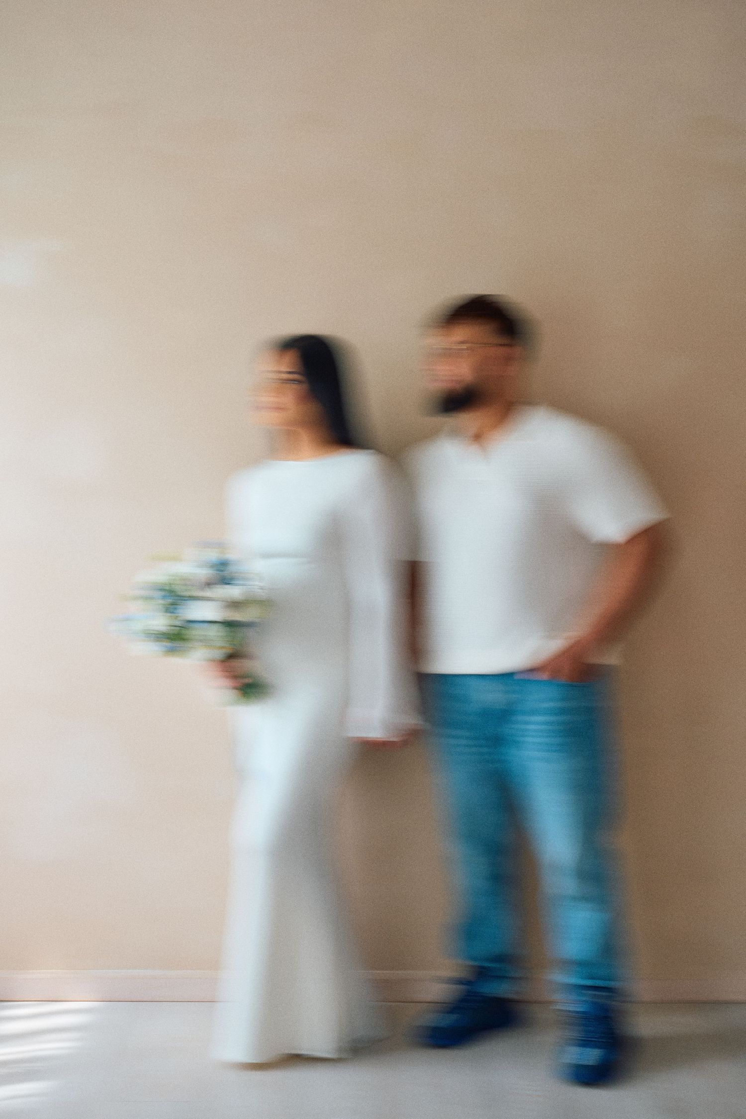 Motion blur sequence shows two figures in white and blue standing against beige wall with increasing movement effect.