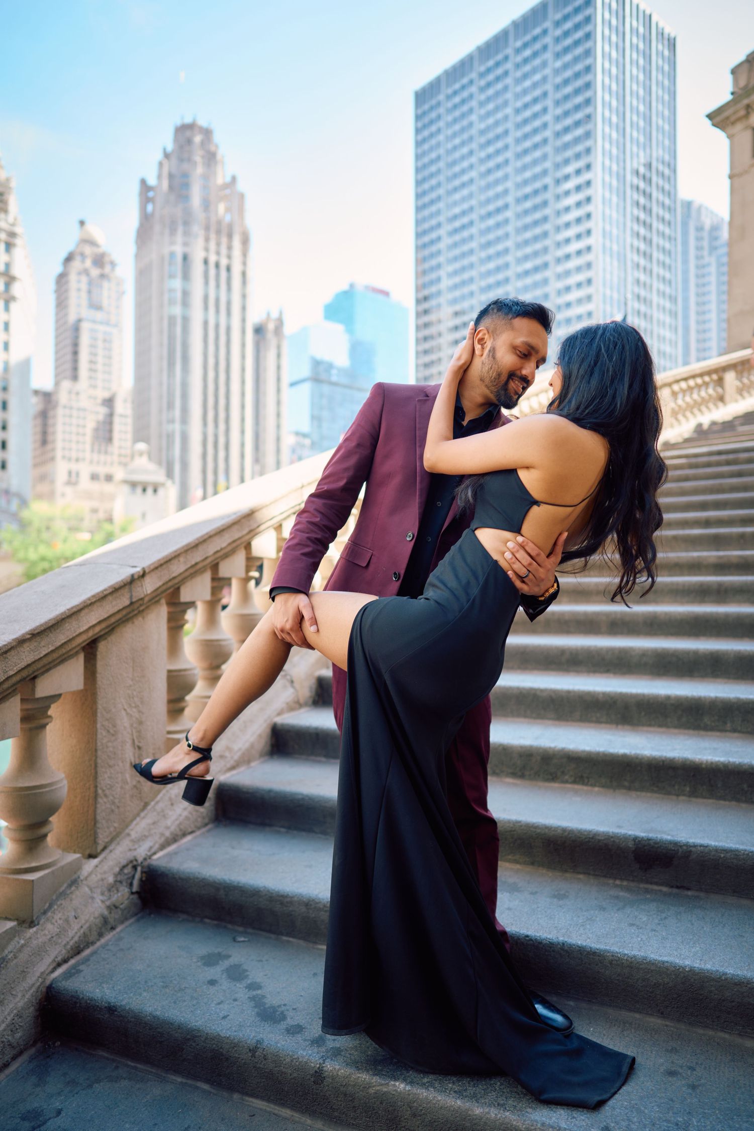 Romantic engagement photo on stone steps in Chicago with iconic skyscrapers in background.