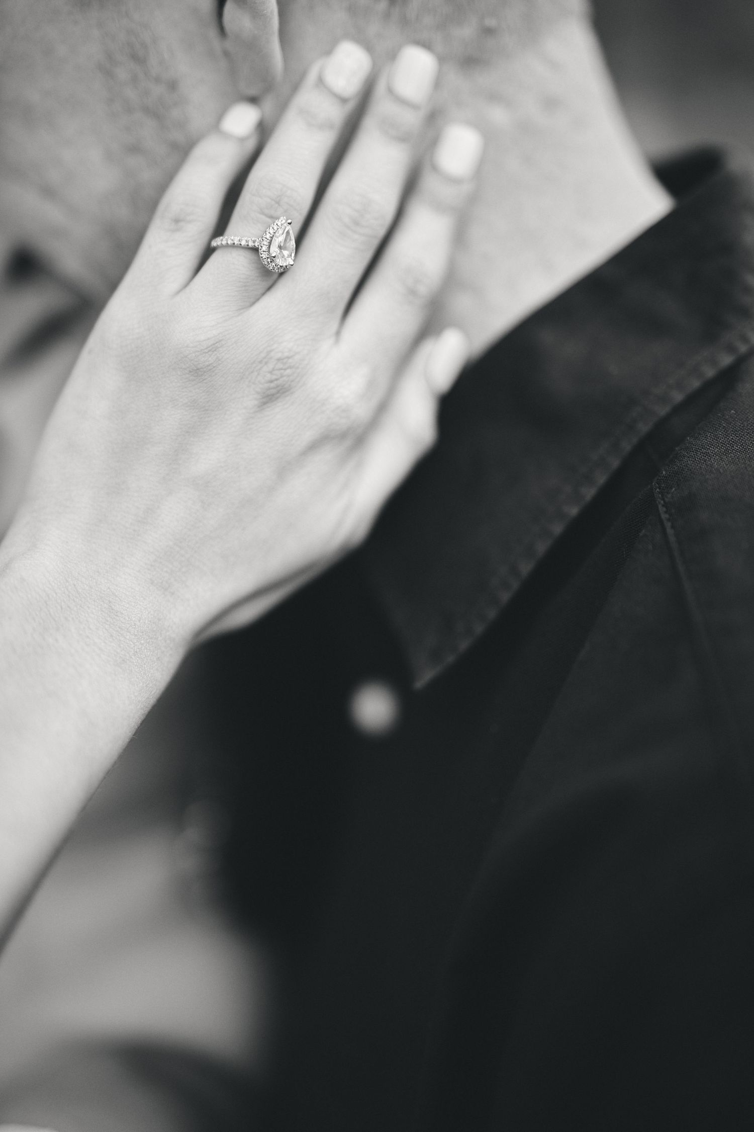 A delicate hand wearing an elegant diamond engagement ring shown in classic black and white photography.