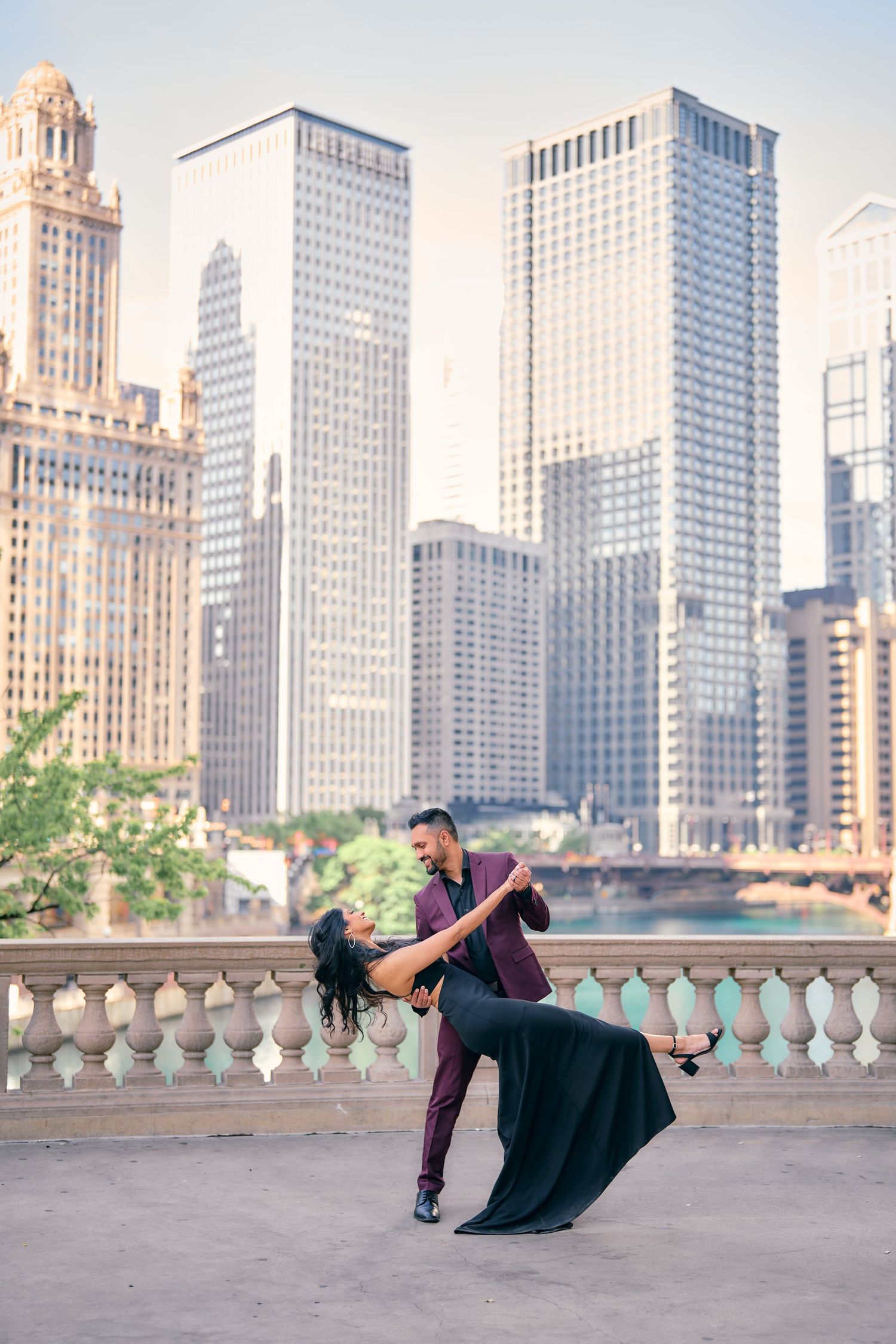 A couple dances romantically on a balcony overlooking the Chicago skyline with tall skyscrapers in the background.
