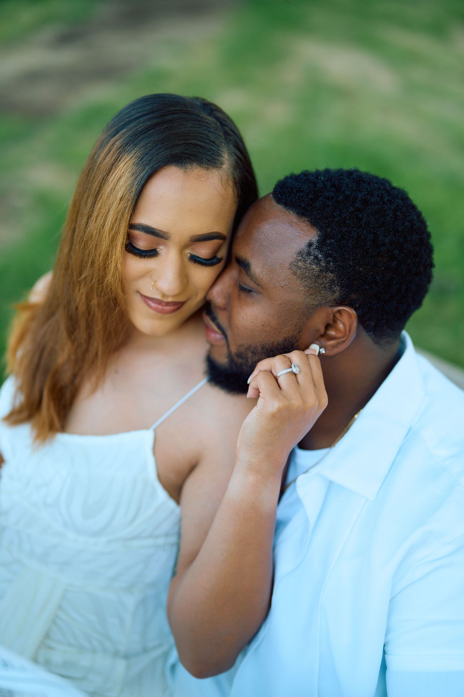 Romantic interracial couple sharing an intimate moment outdoors with natural greenery in background.