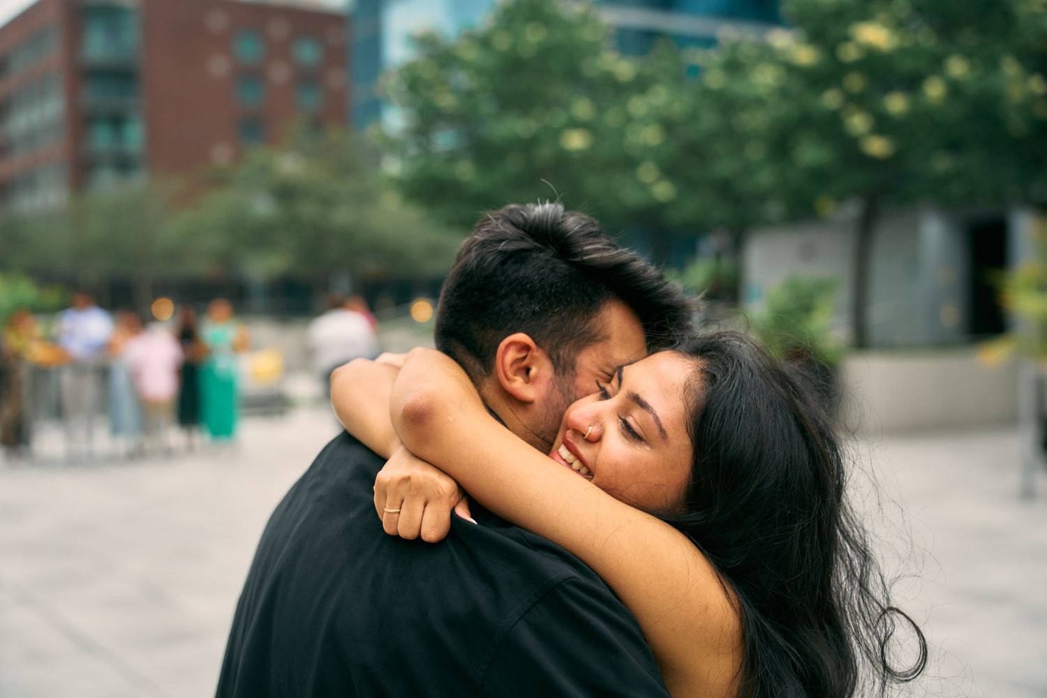 A couple sharing an intimate embracing moment together on a city sidewalk as they hug each other warmly.