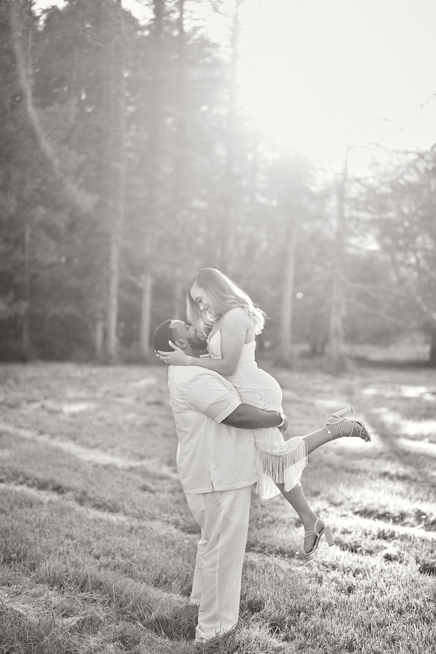 Black and white portrait of couple sharing joyful lift in outdoor setting.