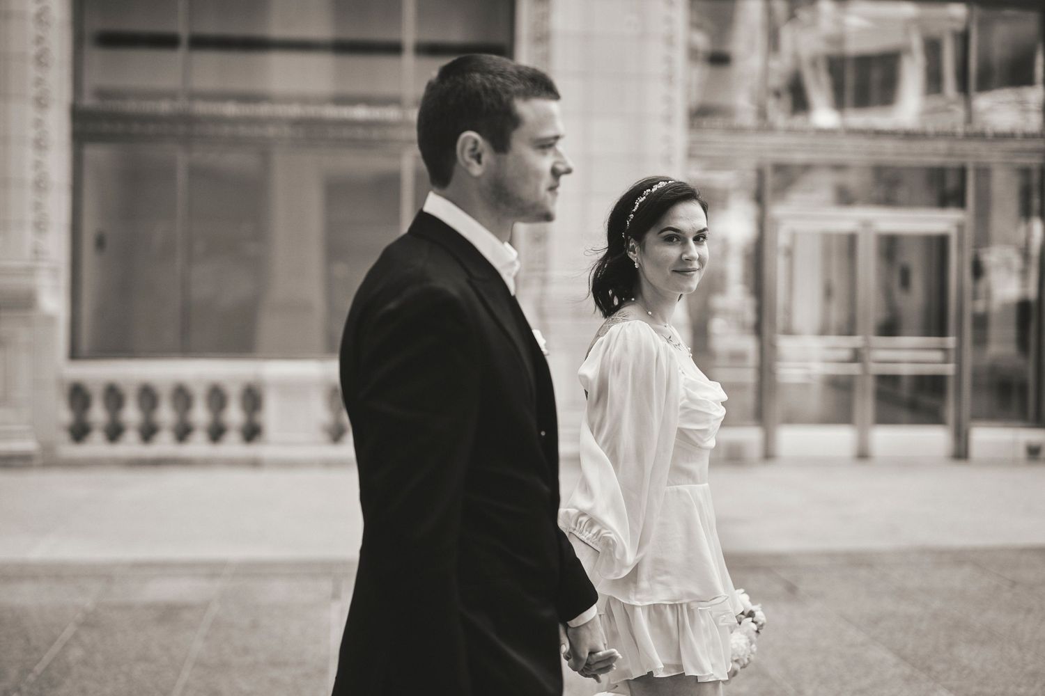 A black and white vintage style wedding photo features a couple standing side by side in formal attire.
