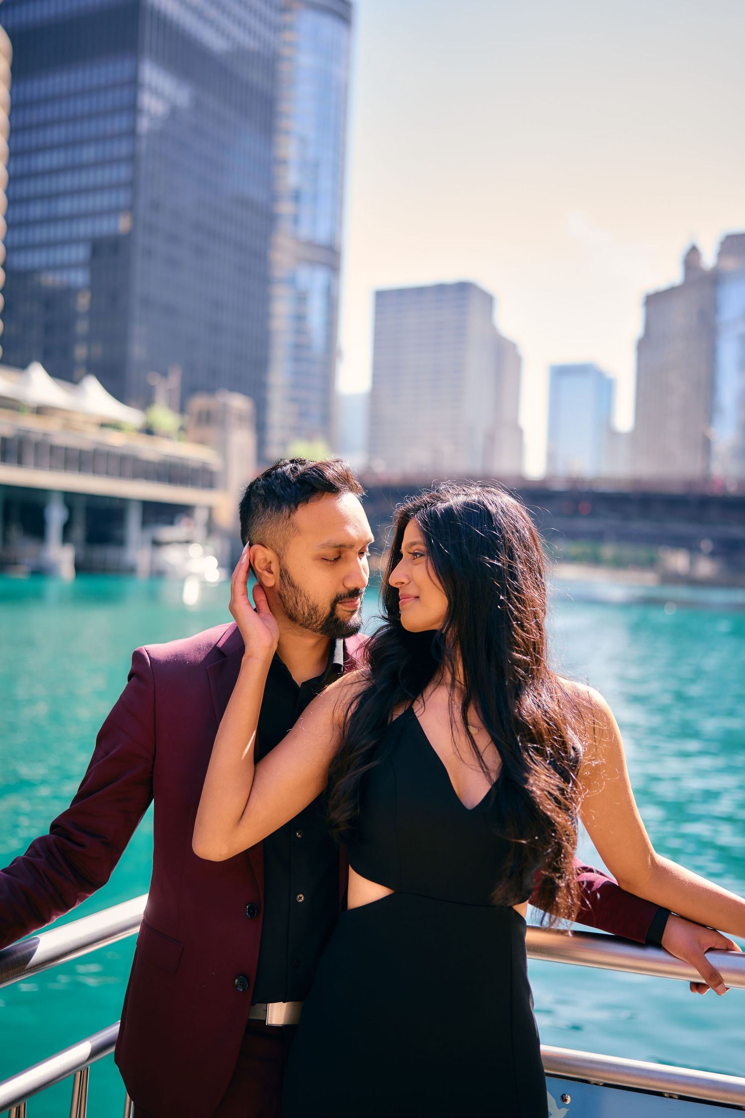 Romantic couple embracing on a boat with Chicago's skyline and turquoise river waters in the background.