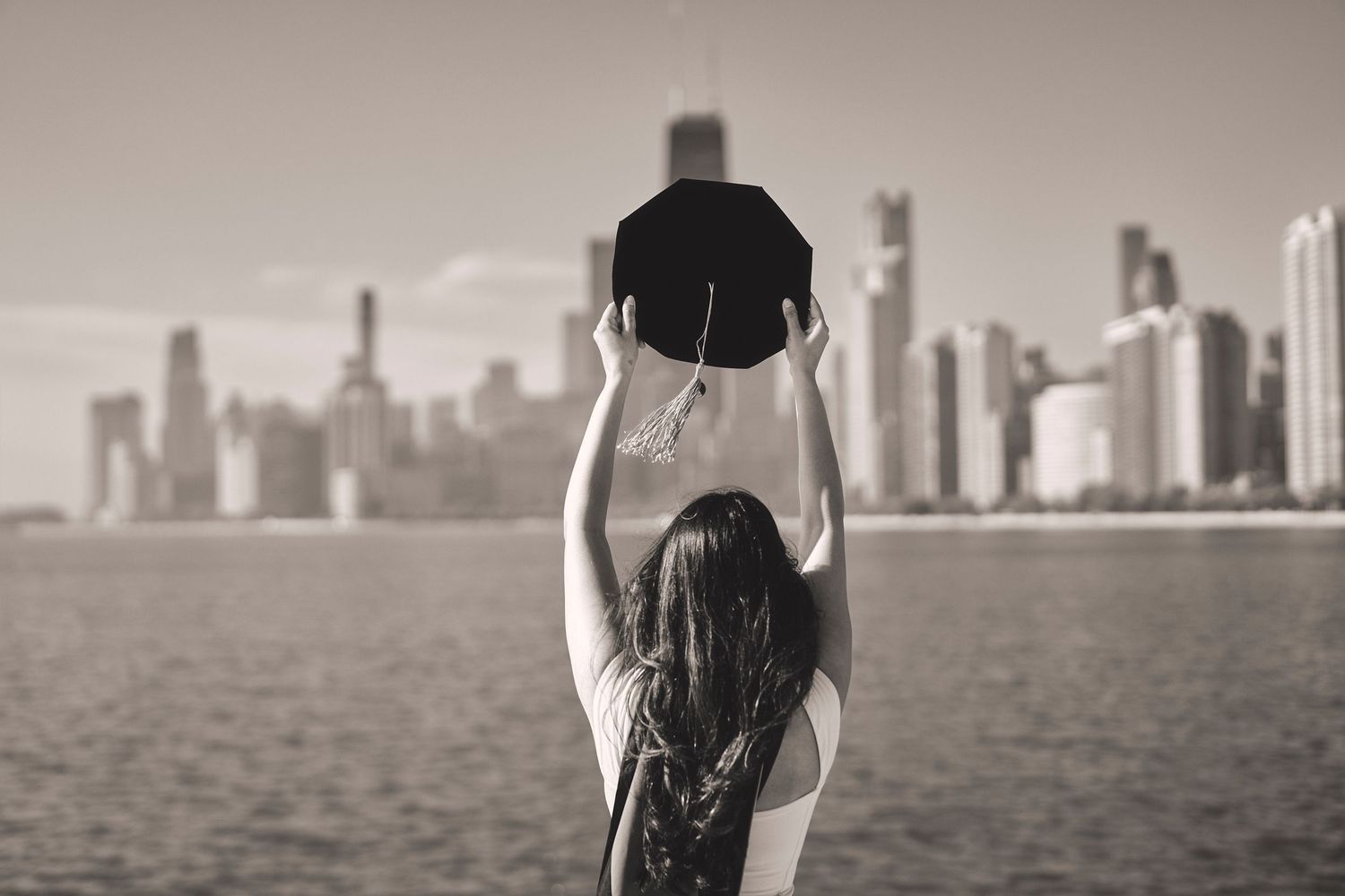 Panoramic series of black and white photos showing a person swimming in a lake with city skyline in background.