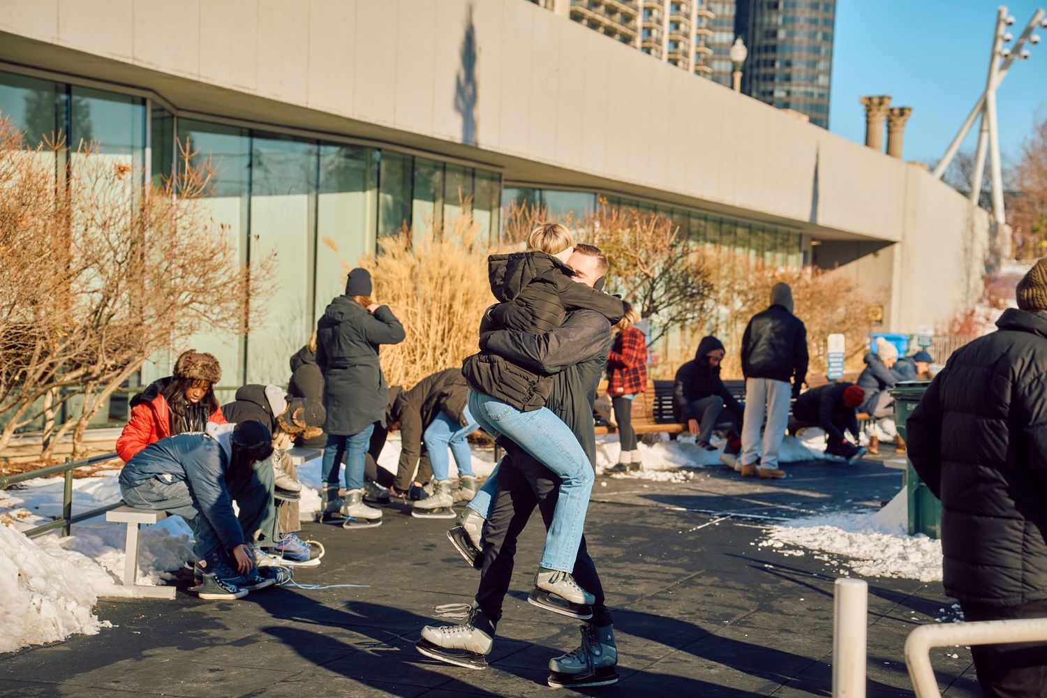 People hugging and greeting each other in a joyful gathering outside a building on a winter day.