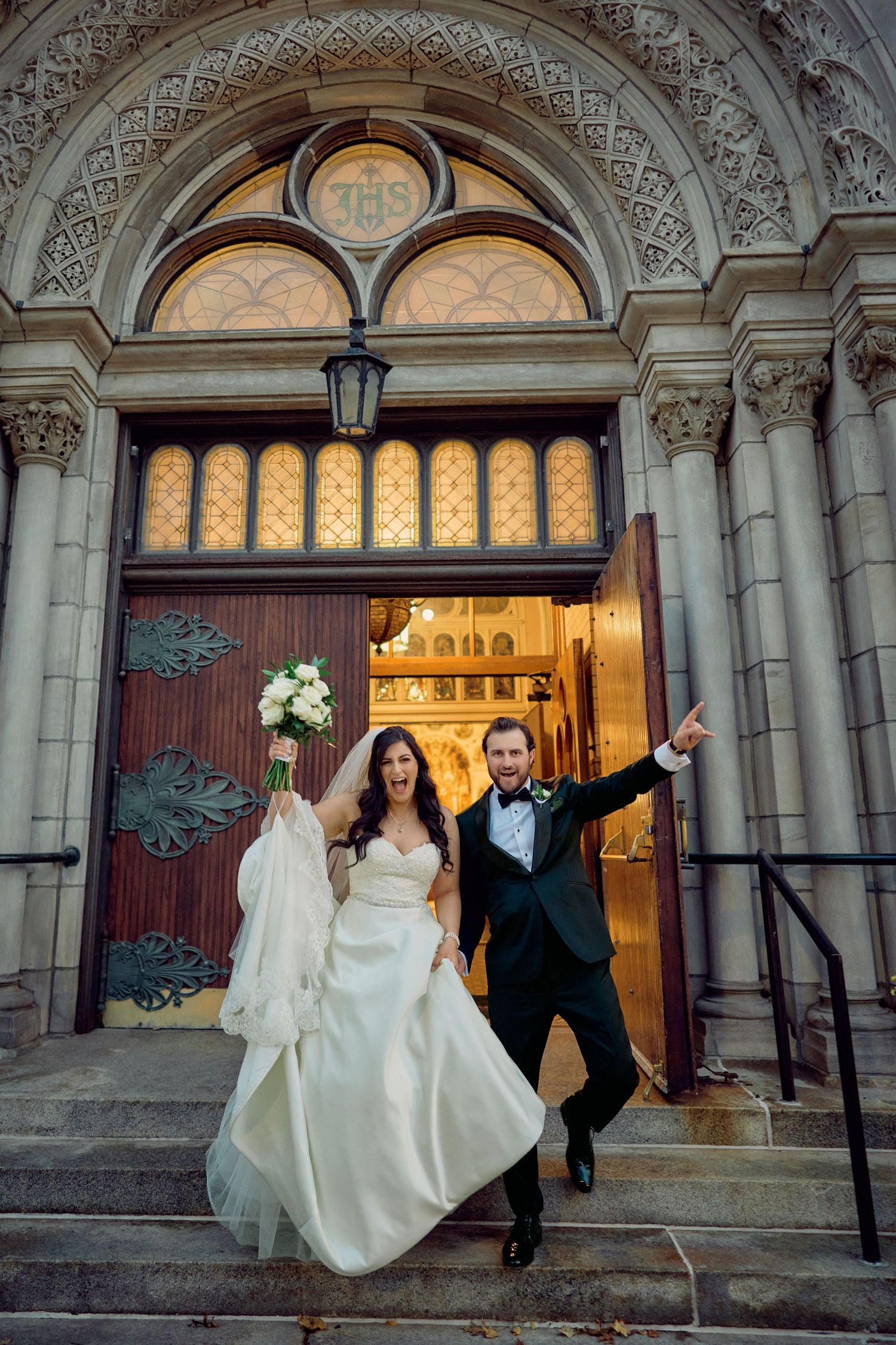 Newlyweds celebrating outside ornate church entrance with beautiful architectural details.