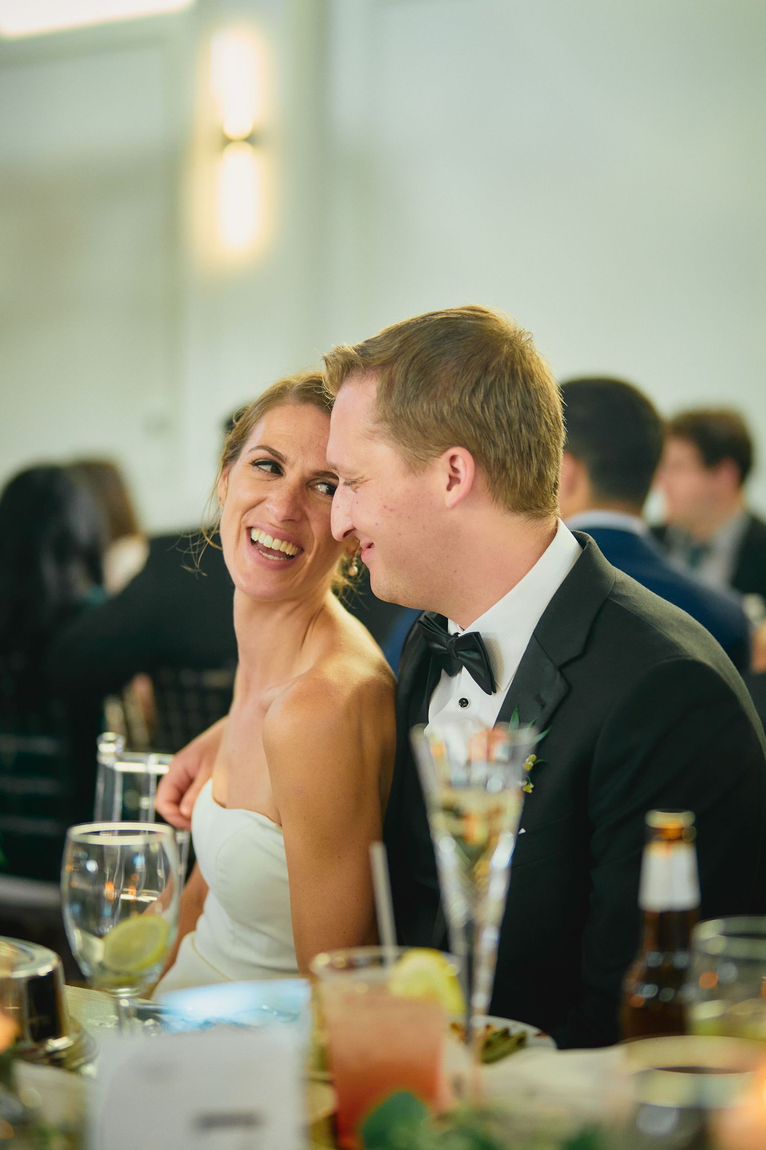 A happy couple shares an intimate moment together during their wedding reception at a formal dinner.