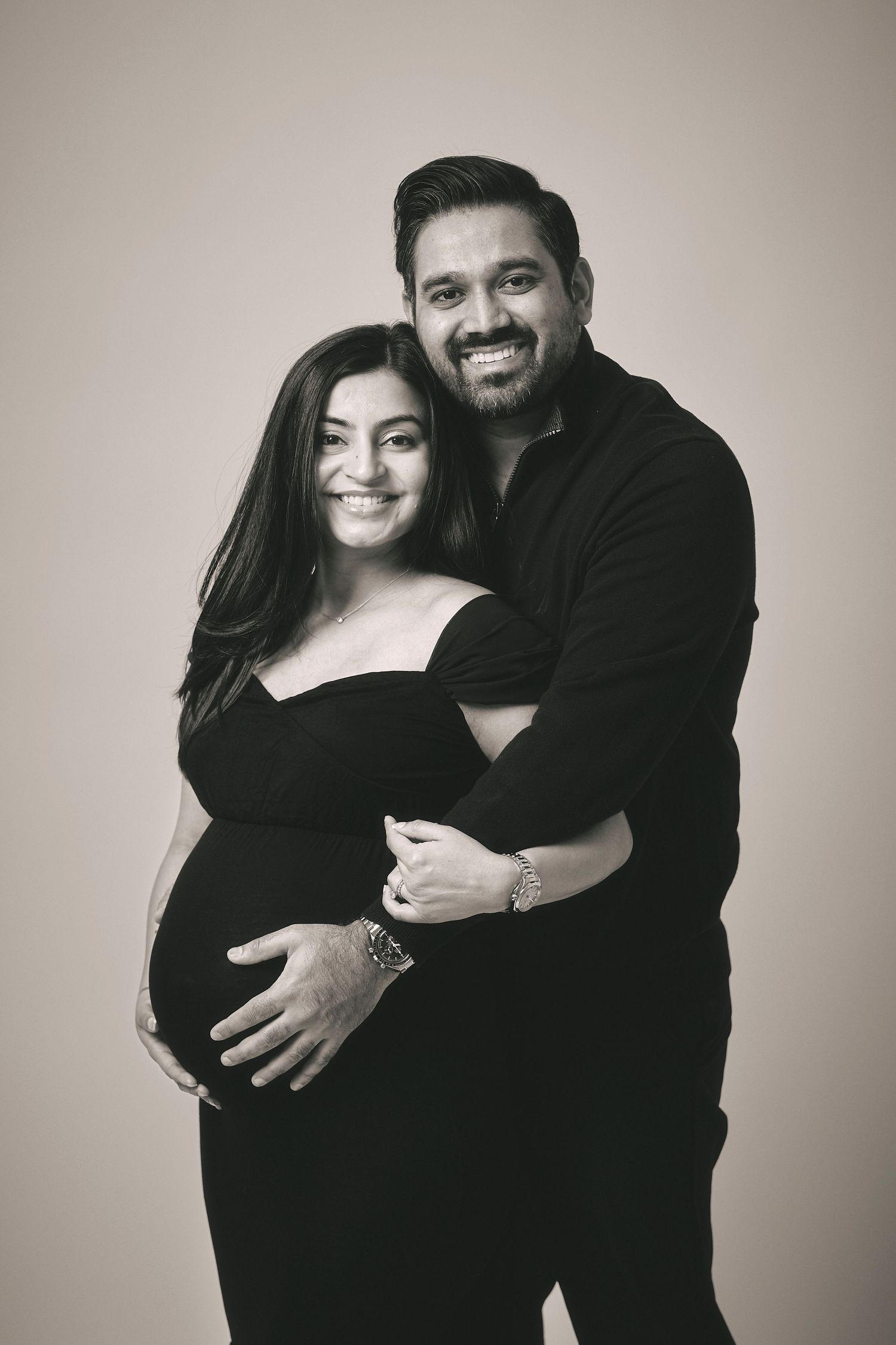 A couple poses together for an intimate black and white maternity photo, showing a tender embrace.