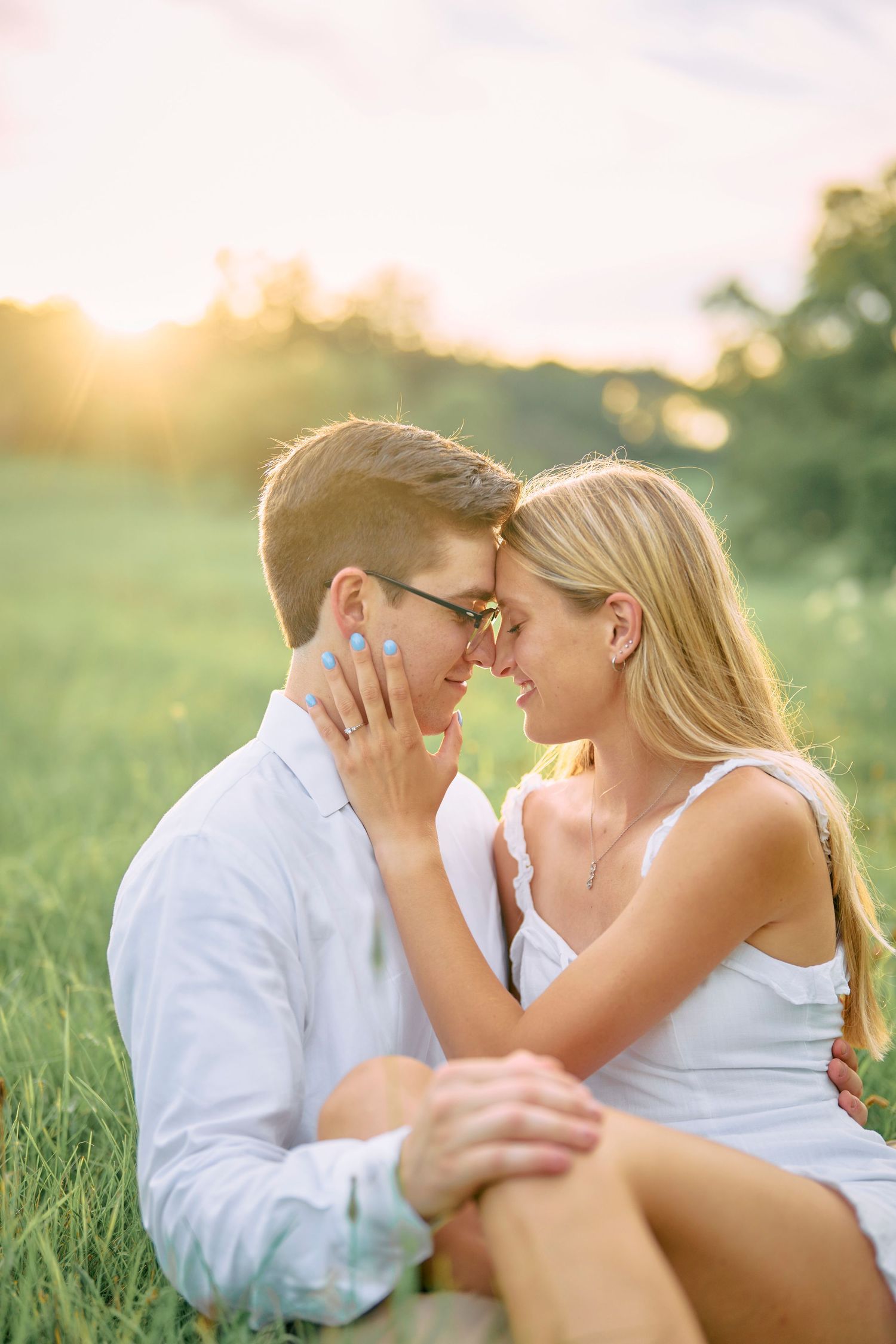A romantic couple shares an intimate moment together in a sunlit meadow at golden hour.
