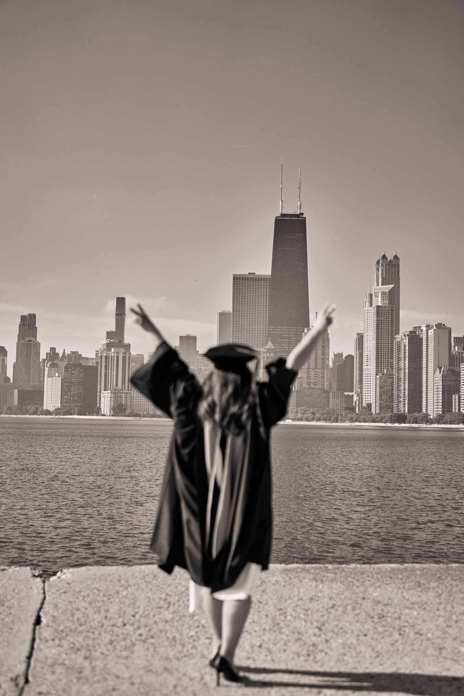 Black and white photo series showing graduates celebrating against Chicago skyline silhouette across Lake Michigan.