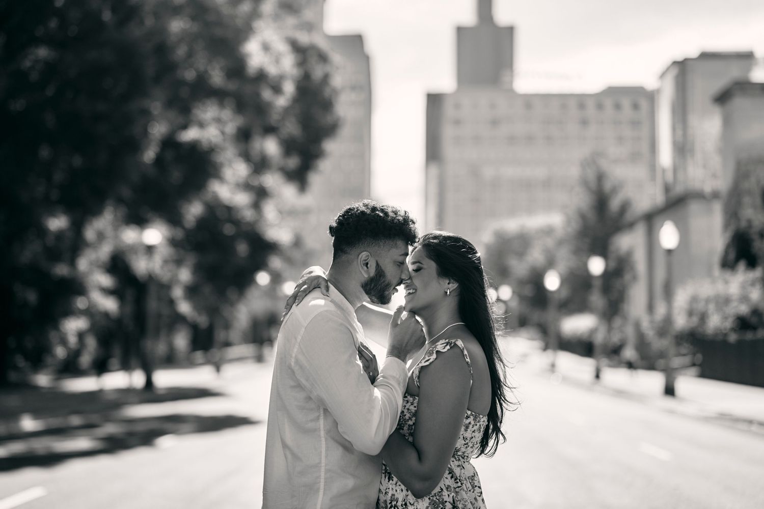 Intimate couple portrait on a city street with urban architecture in the background.