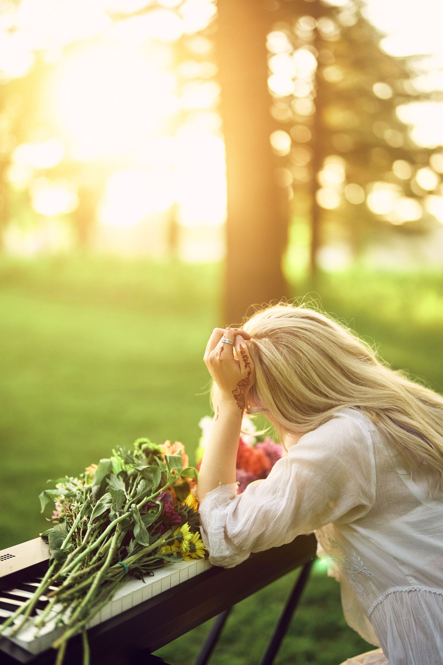 Woman in white dress lying on wooden bench with fresh vegetables and produce in sunlit garden setting.