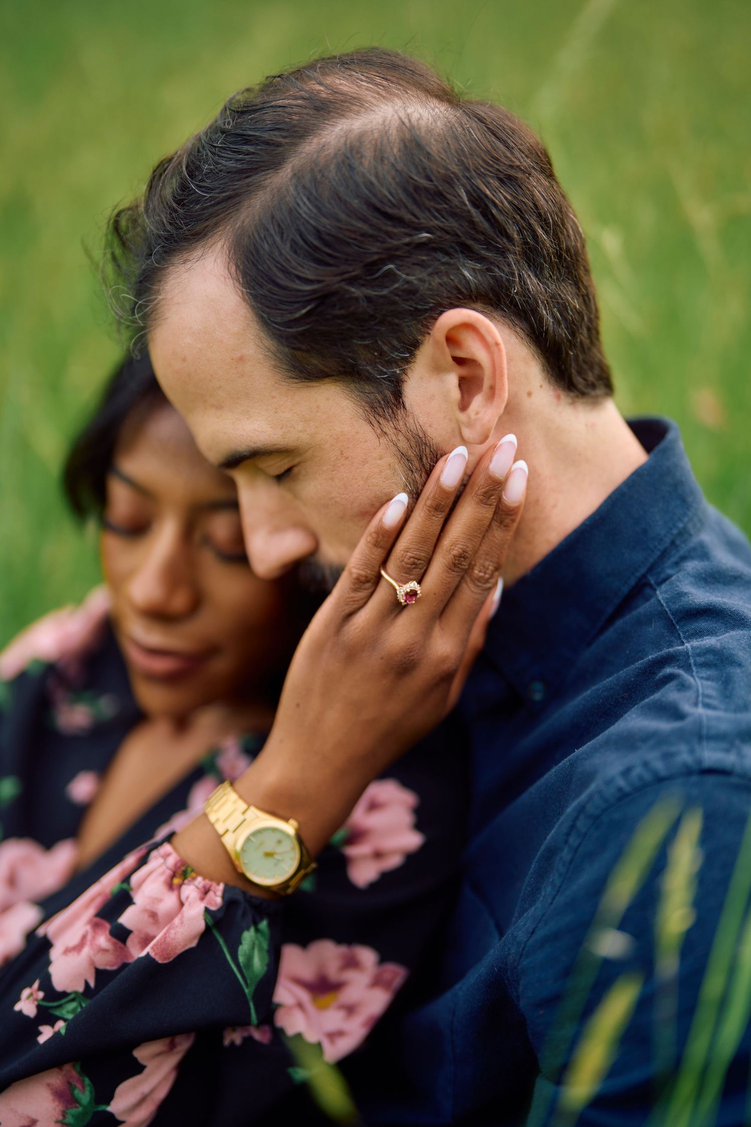 A tender moment between a couple in a garden setting showing intimacy as she touches his face gently.