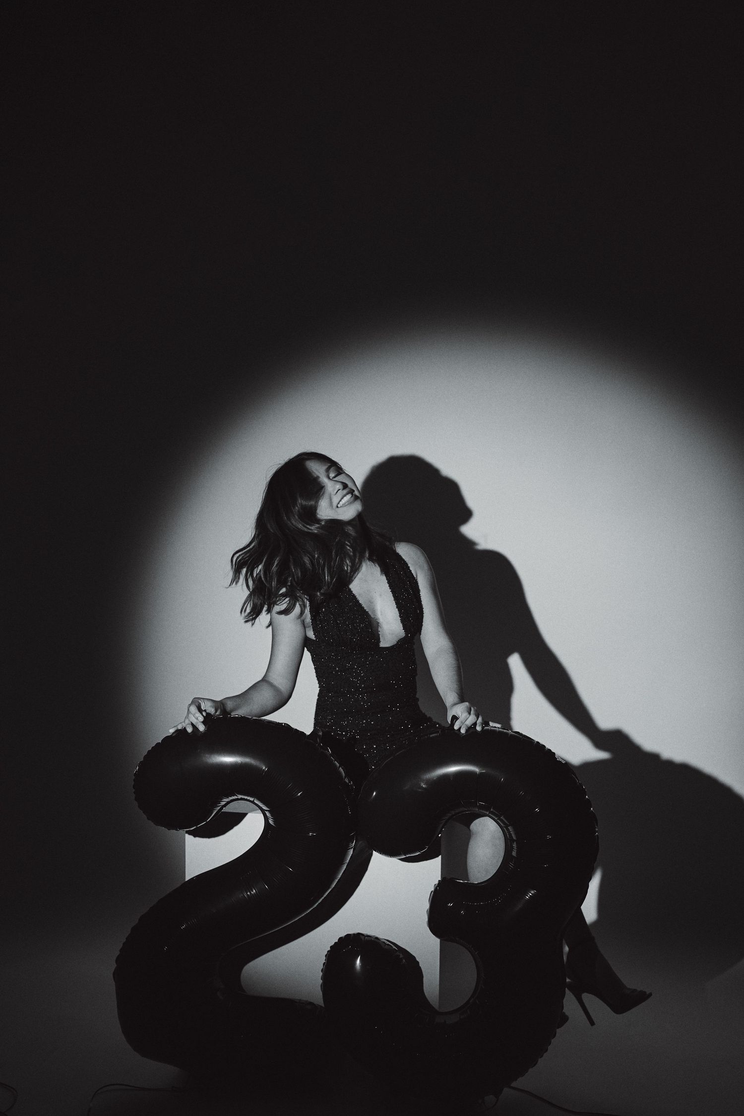 Artistic black and white portrait with number 23 prop and dramatic spotlight.