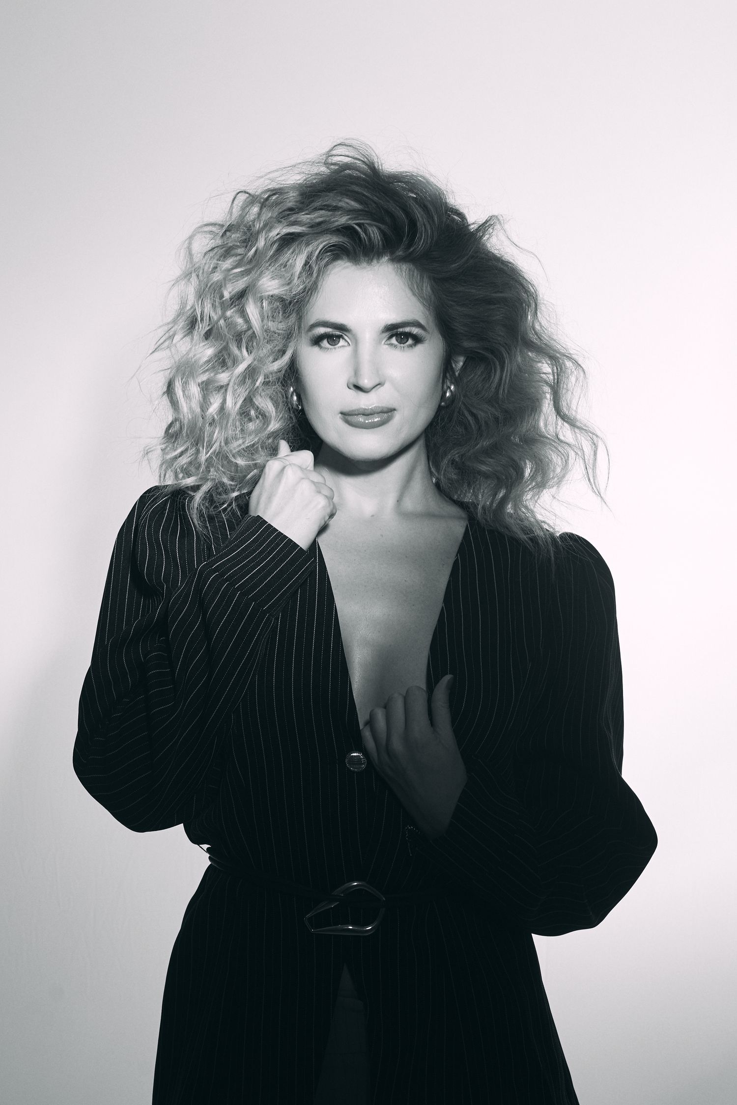 Black and white portrait of woman with voluminous curly hair wearing dark blazer.