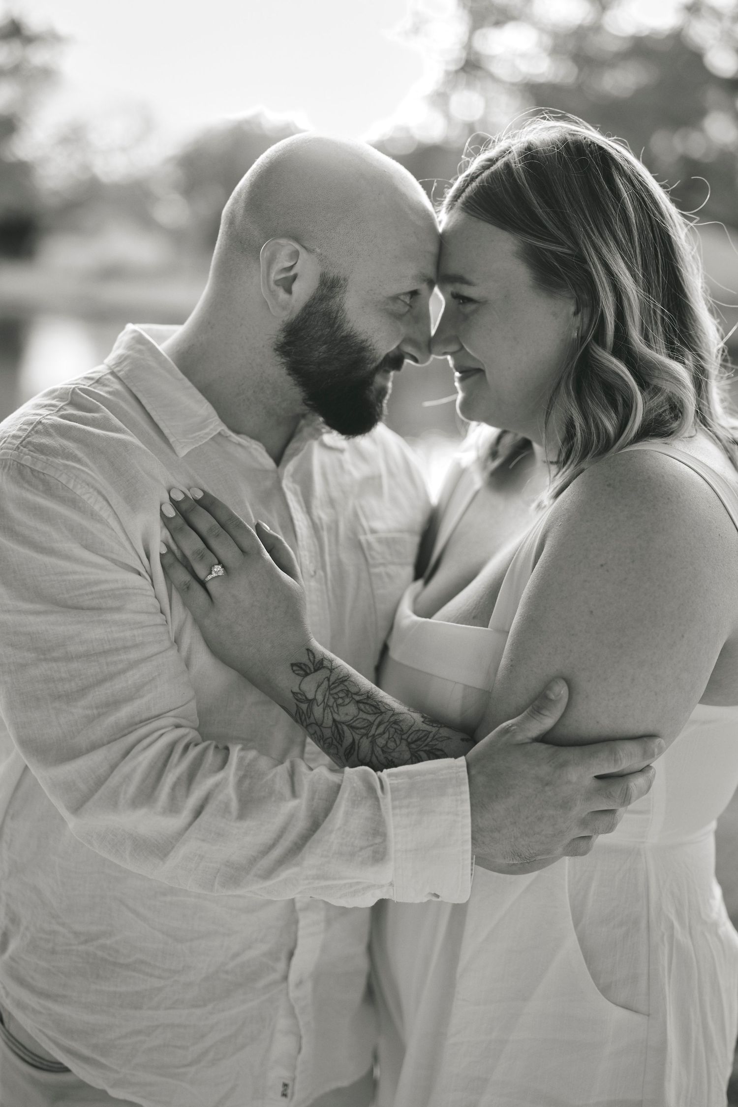 Romantic black and white portrait of a couple in white clothing sharing an intimate moment together outdoors.