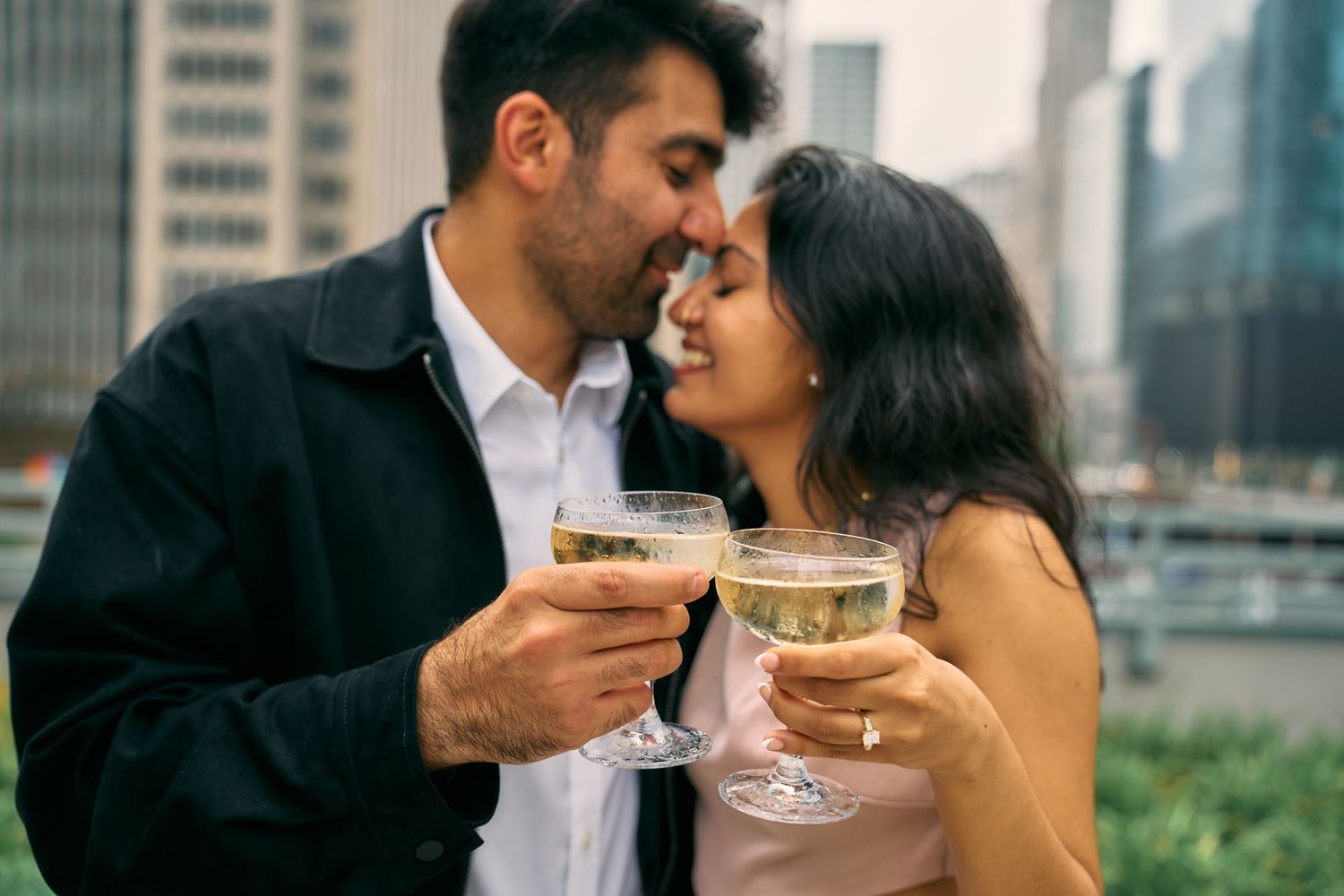 A couple shares cocktails and an intimate moment on an urban rooftop terrace.