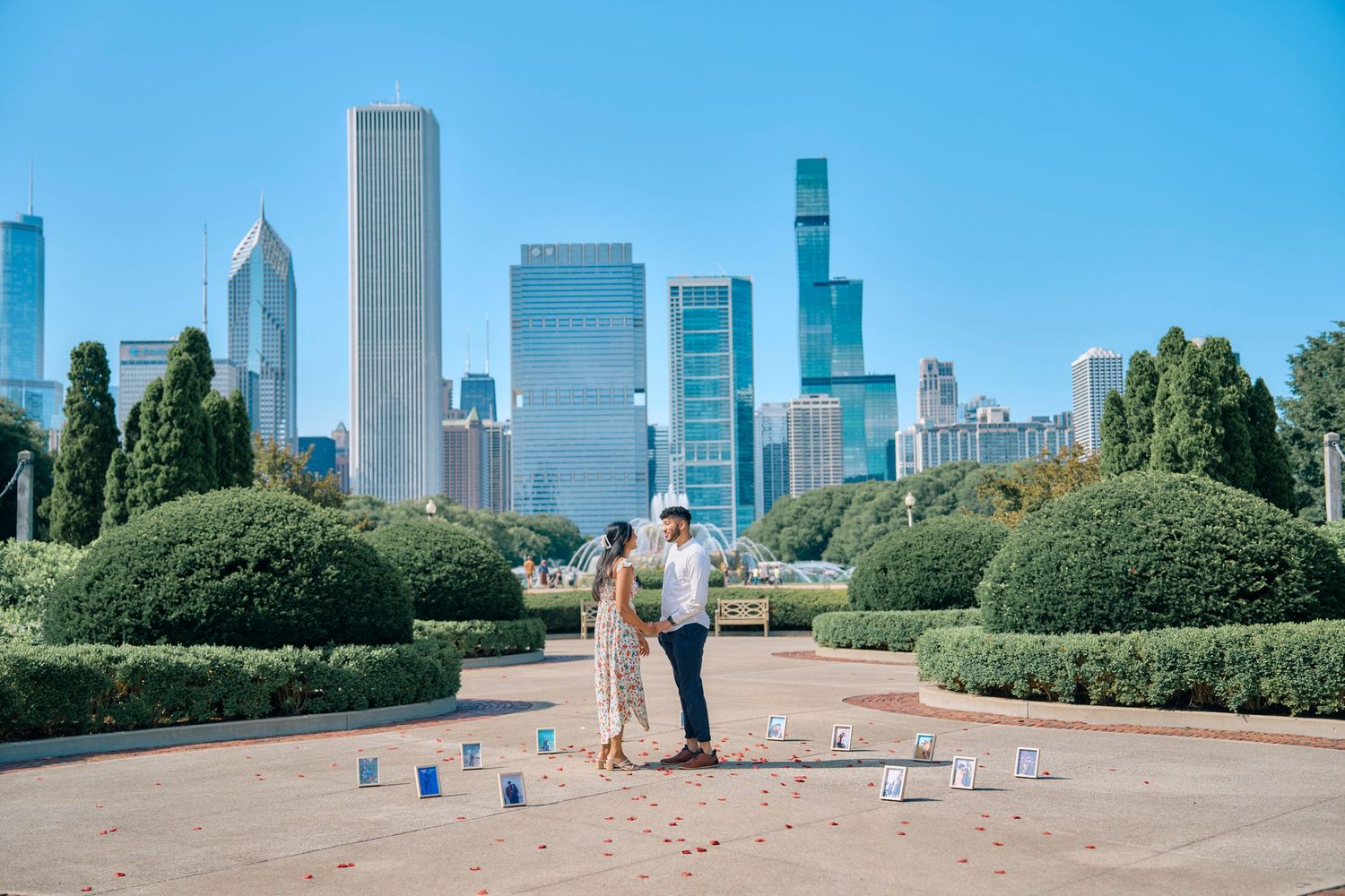 A couple stands in a manicured garden with the Chicago skyline in the background on a sunny summer day.