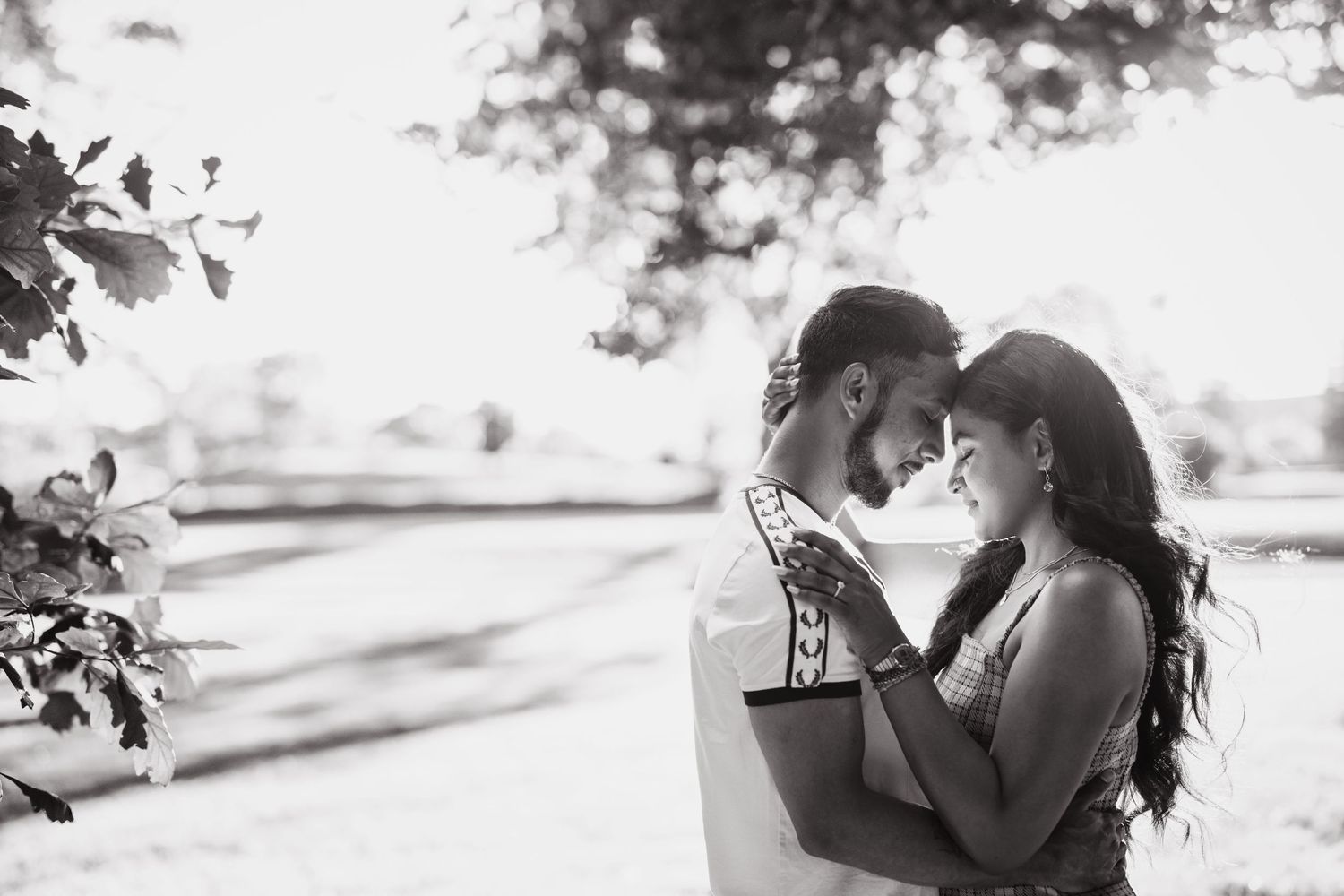 A romantic black and white outdoor photoshoot captures a tender intimate moment between two people.