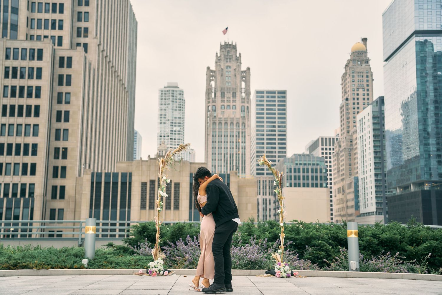 Romantic couple embracing with Chicago Tribune Tower and city skyline in the background.