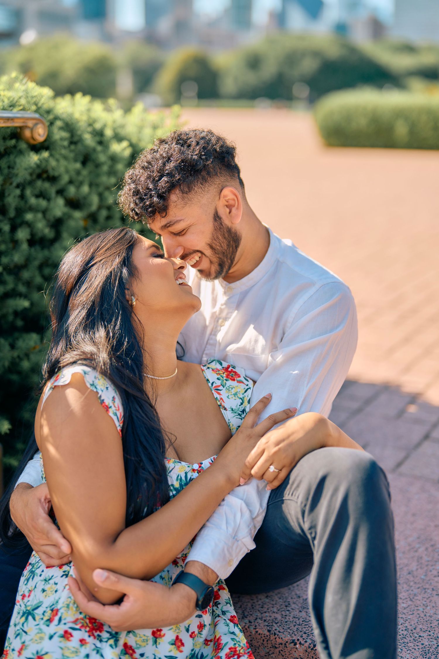 A romantic couple shares a tender moment together outdoors on a sunny day among garden hedges.
