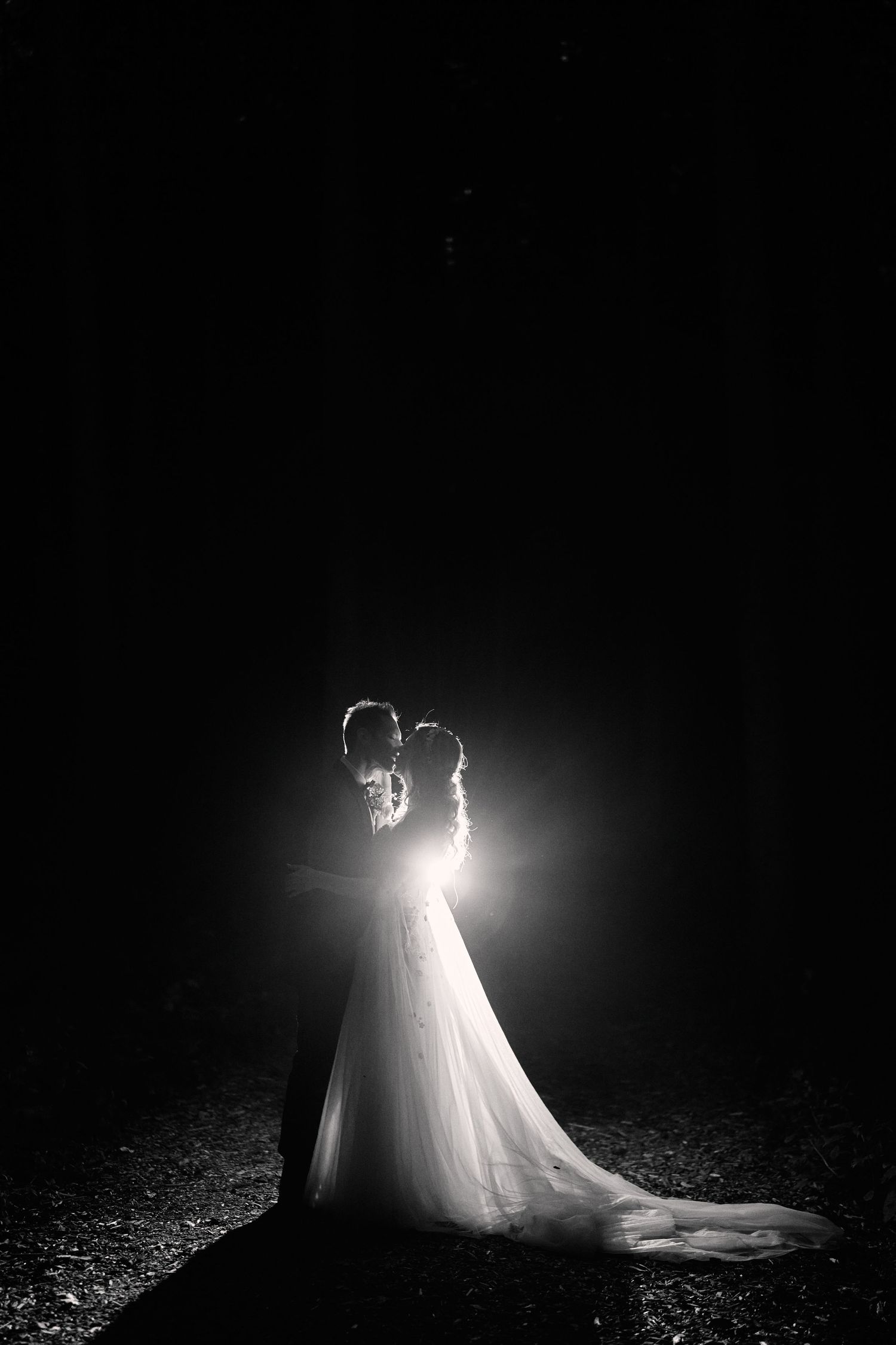A dramatic black and white wedding photo series showing silhouettes of a couple in backlit poses against a dark background.