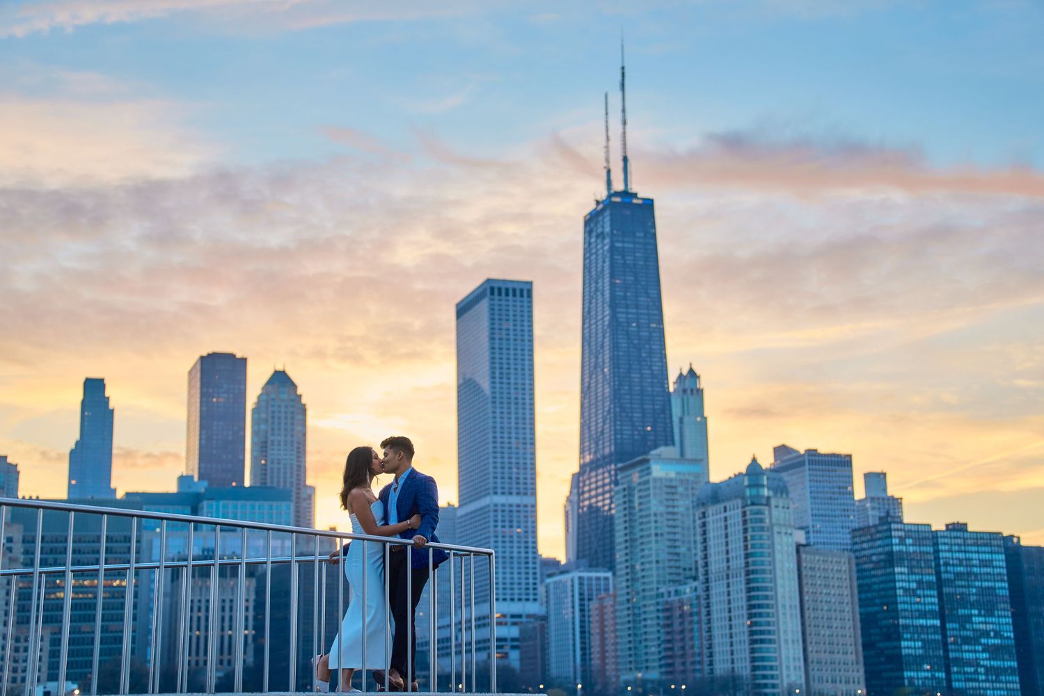 Couple silhouetted against the Chicago skyline at sunset with the John Hancock building in the background.