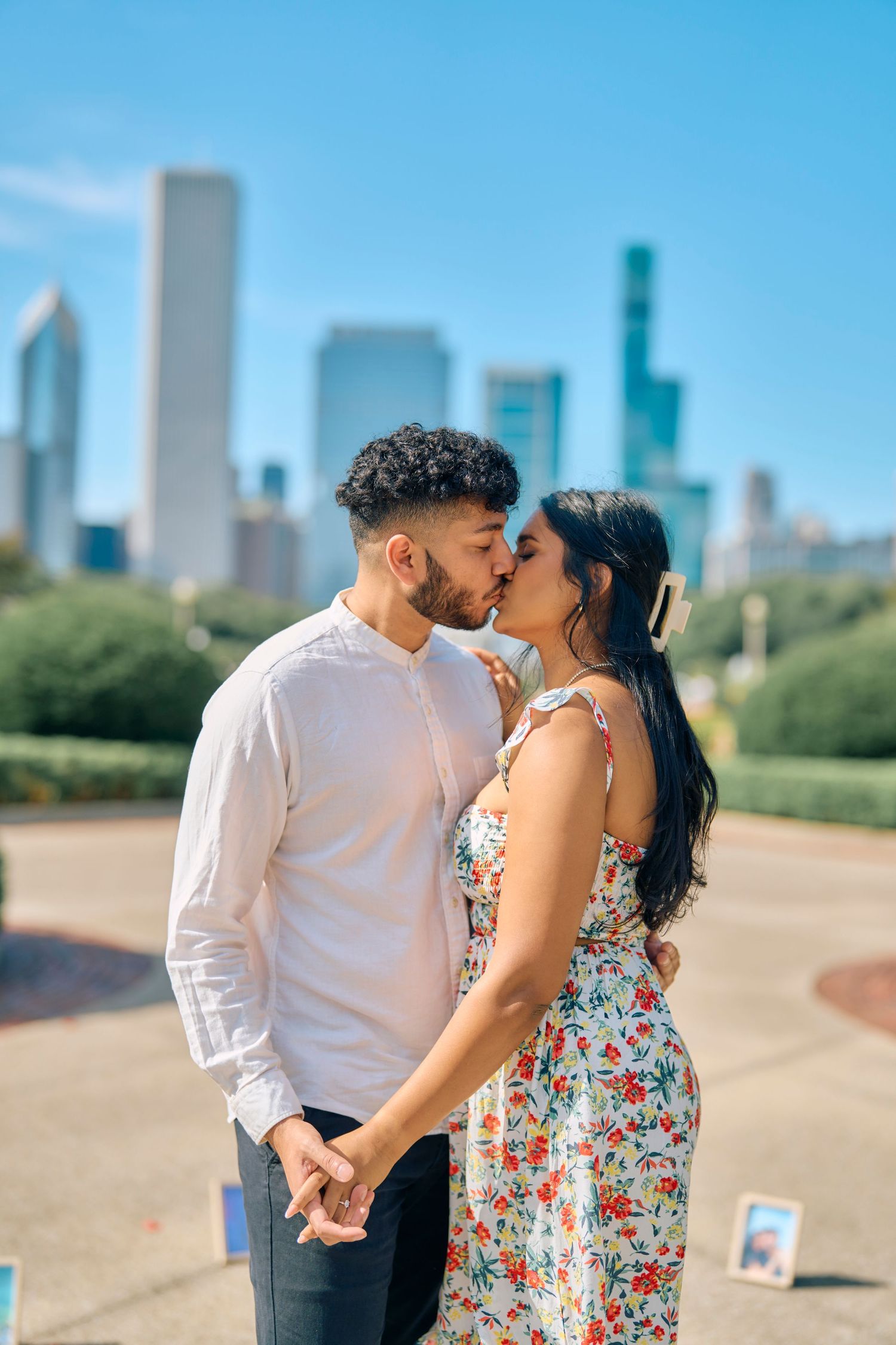 A romantic couple shares a tender kiss in Chicago's Grant Park with the iconic downtown skyline in the background.
