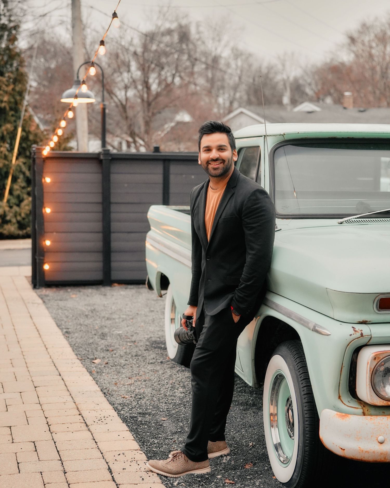 Classic mint green vintage truck with person in black suit standing beside it at dusk.