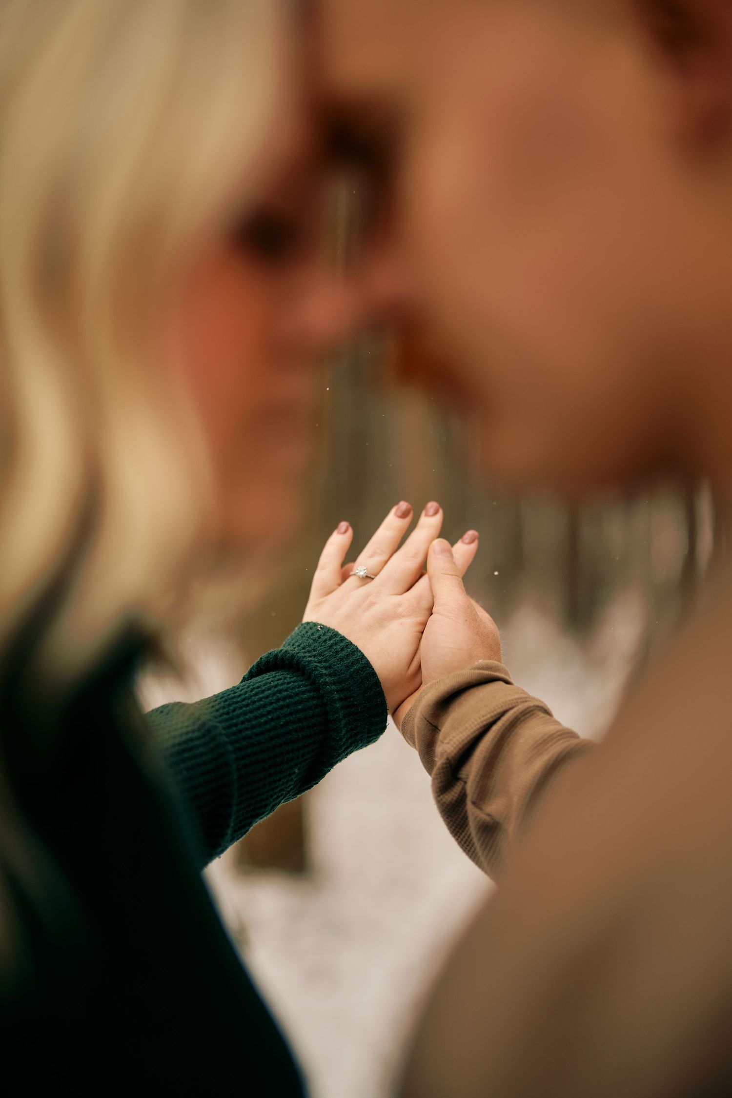 Two people share a high-five moment wearing green and brown sweaters in a warm indoor setting.