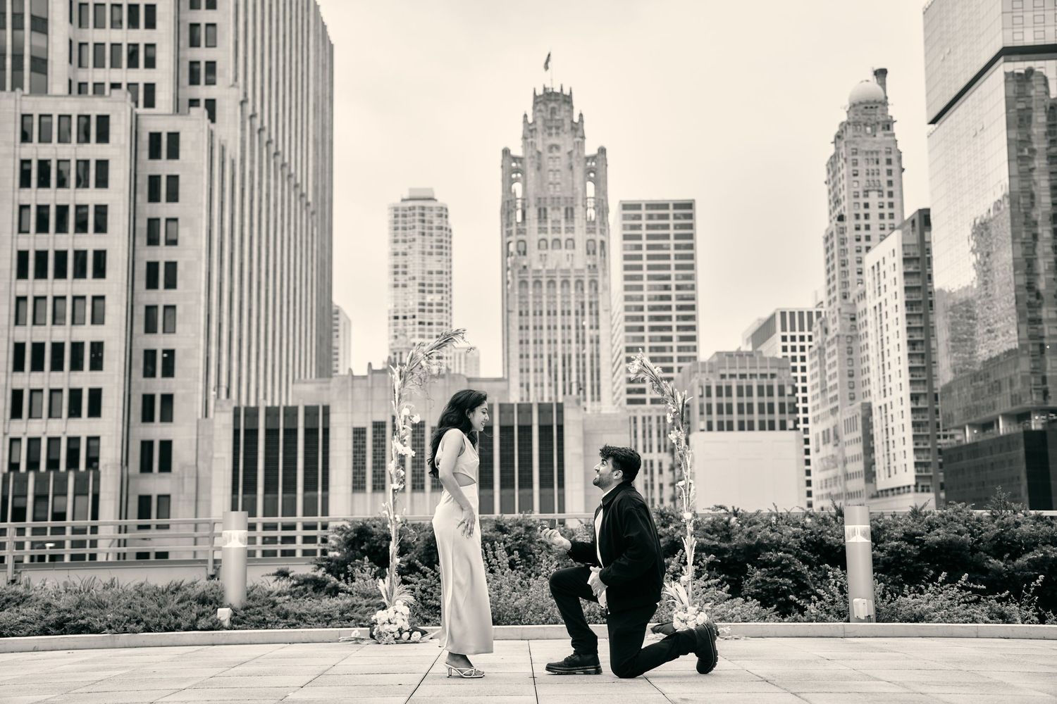 A romantic black and white proposal moment photographed in New York City with skyscrapers in the background.