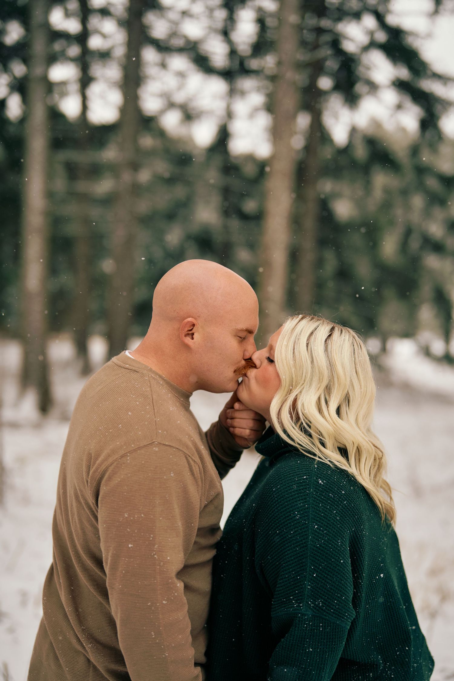 A romantic winter scene of a couple sharing an intimate moment in a snowy forest setting.