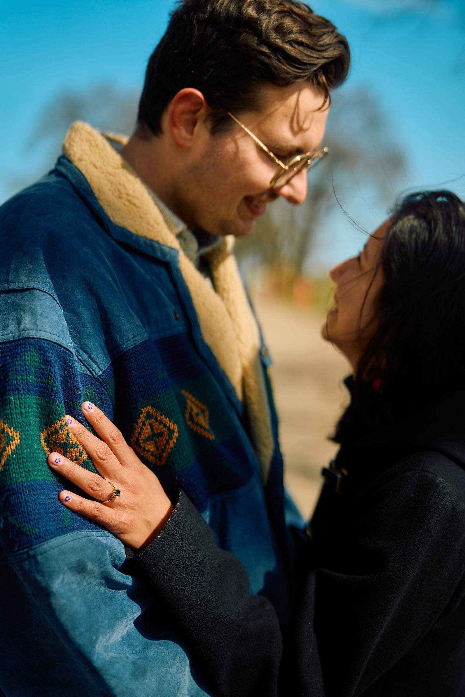 Couple sharing an intimate moment outdoors wearing winter clothing as one gently touches the other's chest.