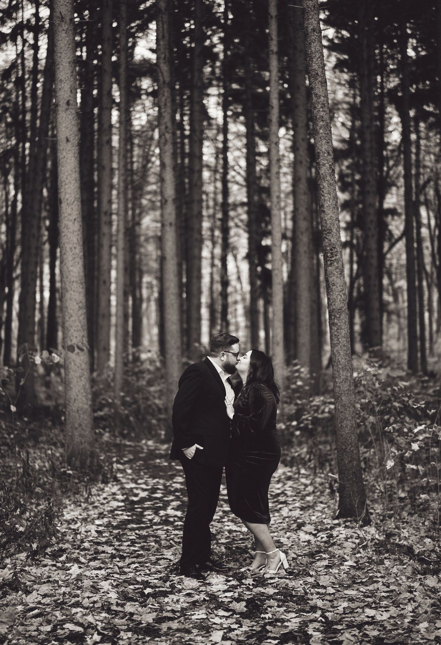 A romantic black and white photo of a couple sharing an intimate moment in a misty forest.