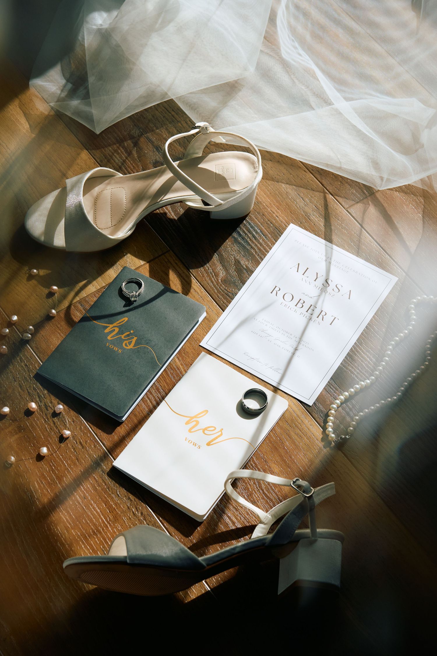 A series of wedding invitation cards and envelopes arranged artistically on a rustic wooden surface with soft tulle fabric.