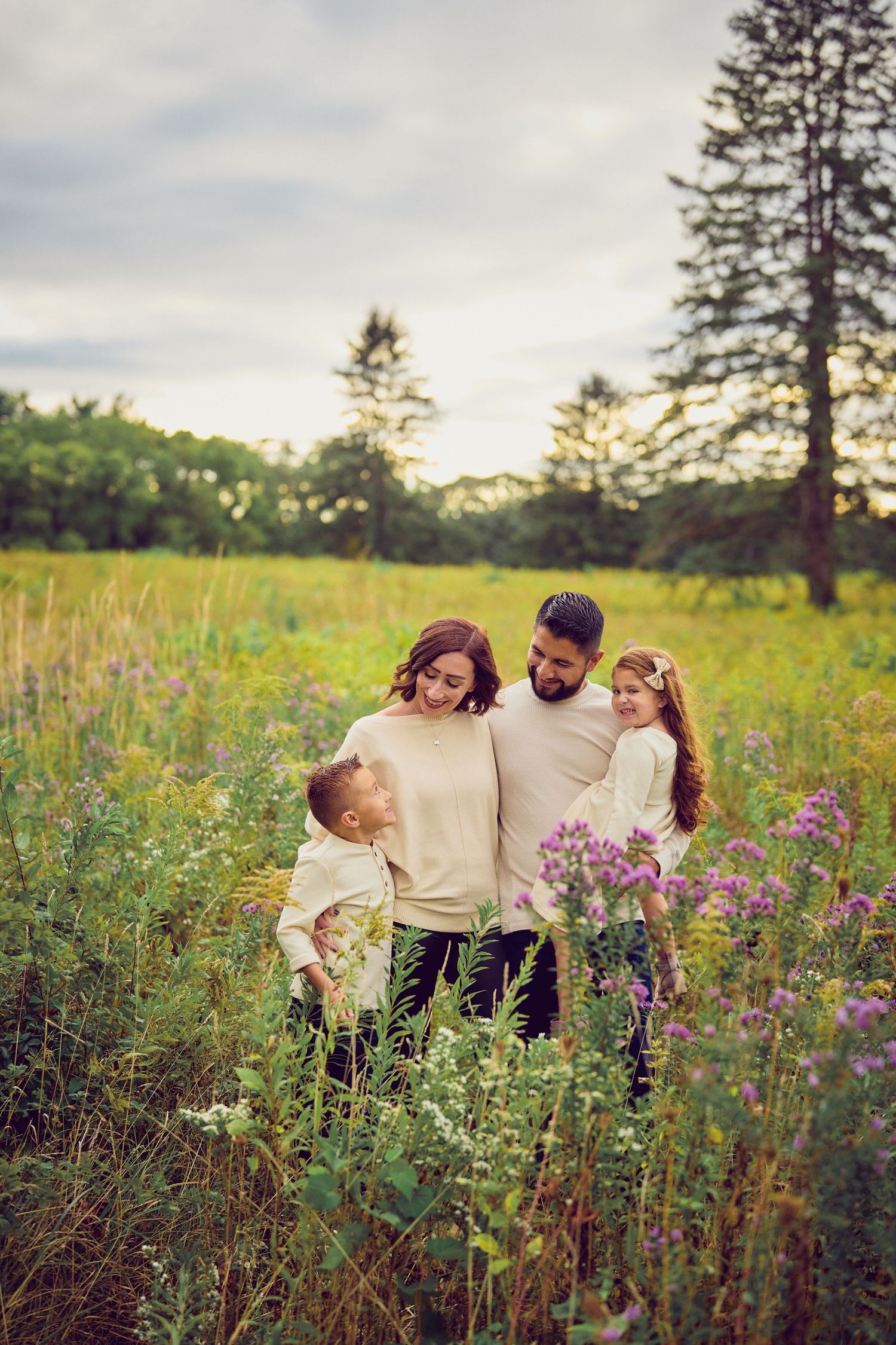 Family enjoying a golden hour moment together in a summer meadow filled with vibrant wildflowers.