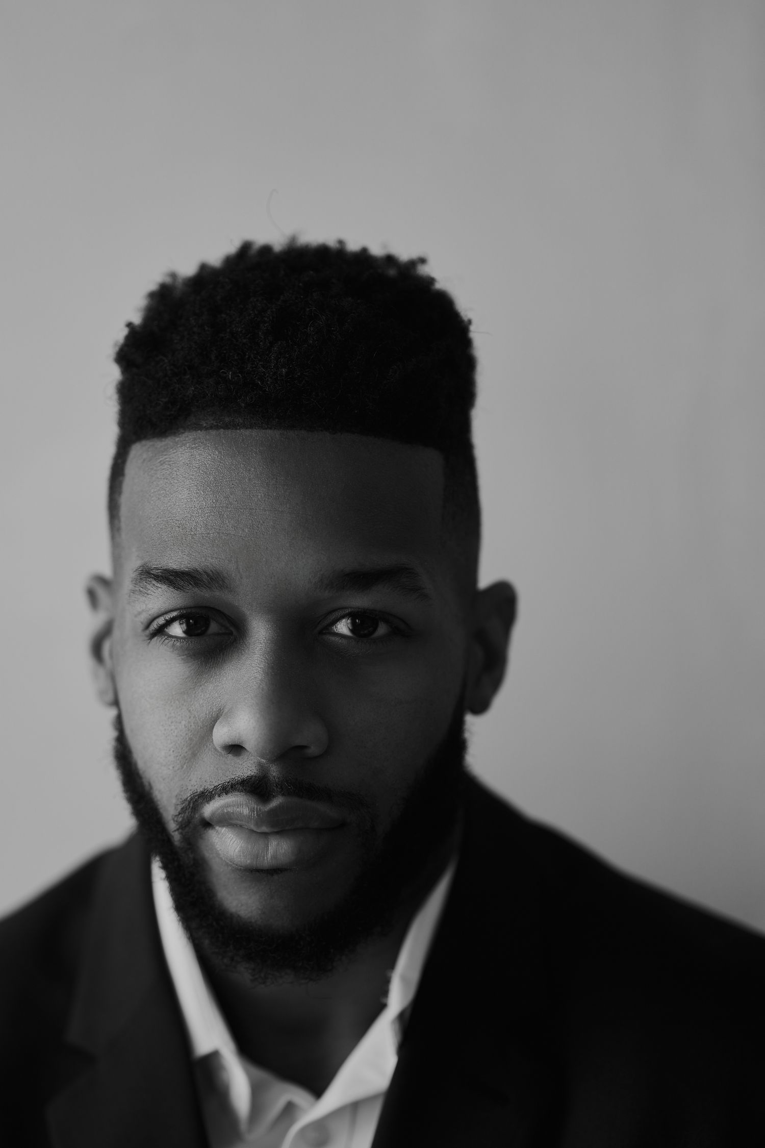 Black and white close-up professional headshot portrait with dramatic lighting.