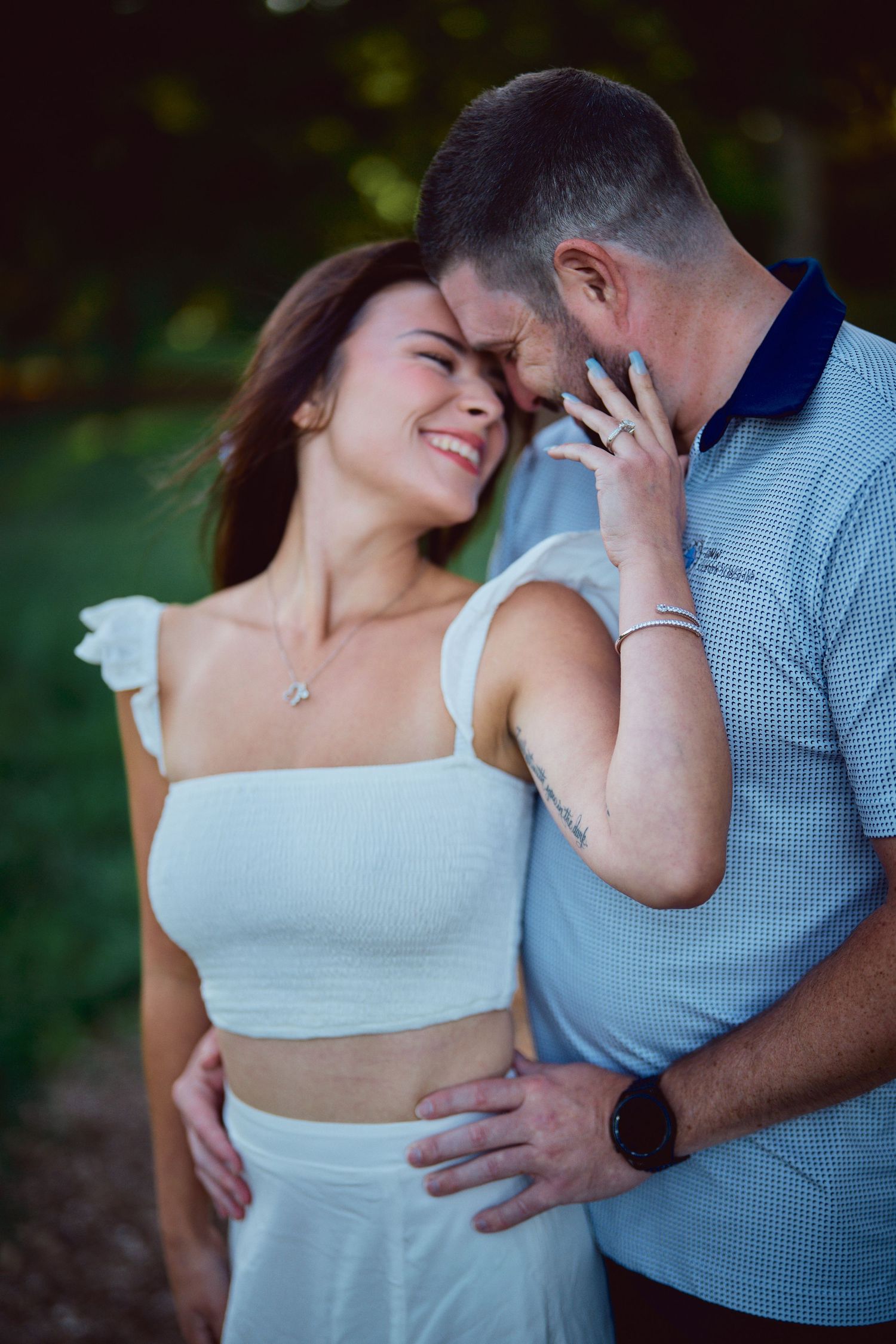 A romantic couple shares an intimate moment outdoors while dressed in casual summer attire.