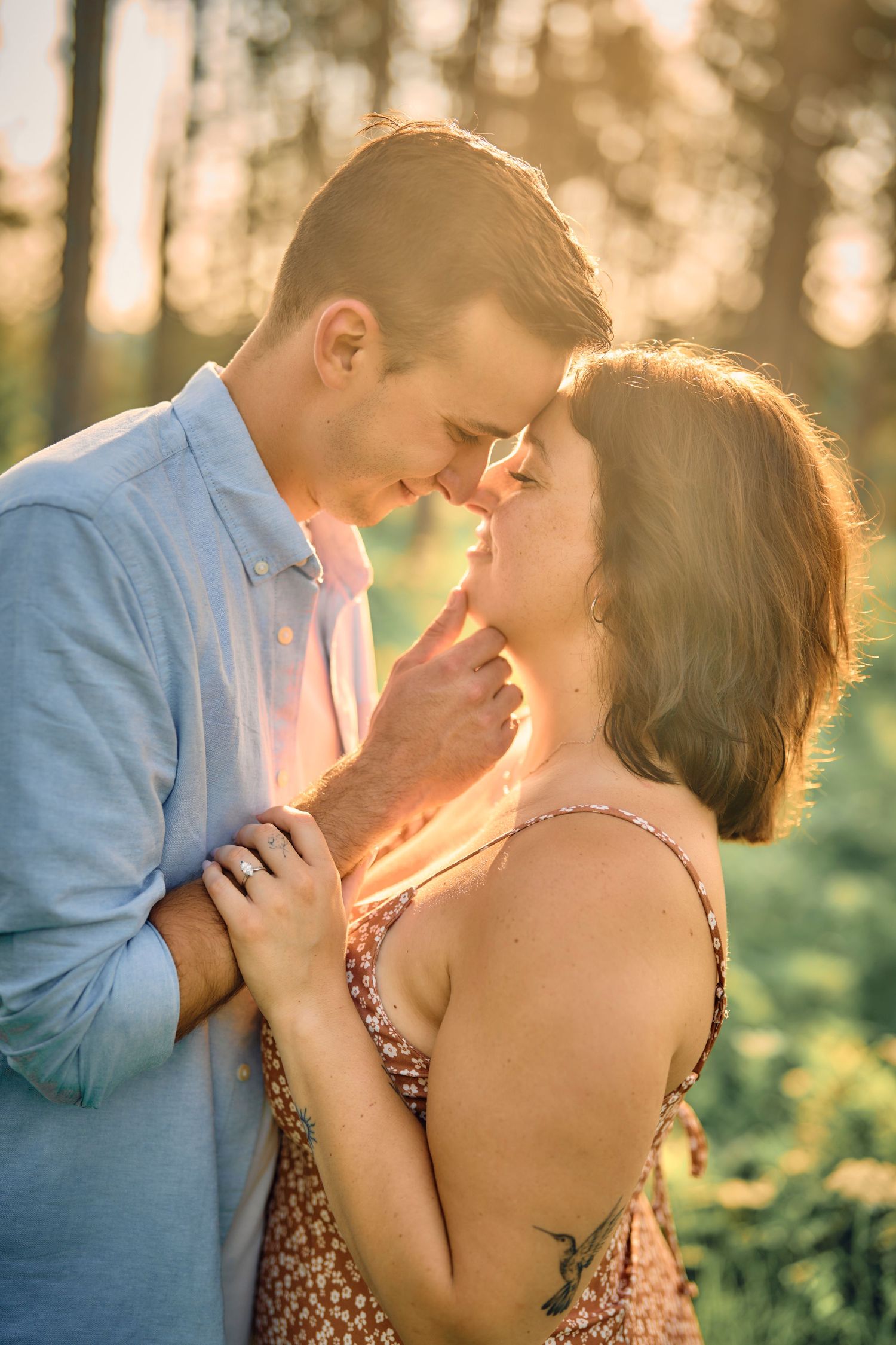 A romantic couple embraces in a sun-drenched field during golden hour as they share an intimate moment together.